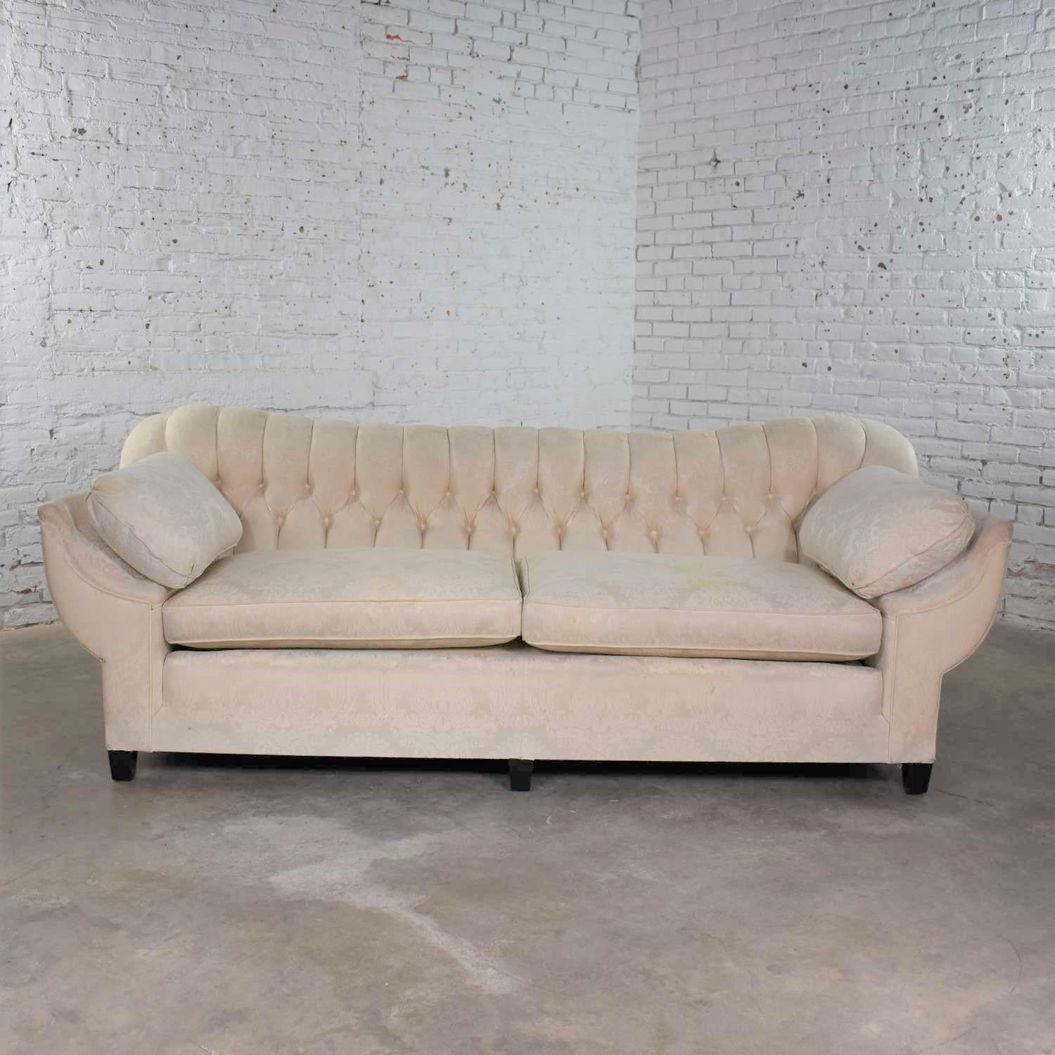 Fabulous vintage Art Deco or Hollywood Regency sofa with a tufted back and concave pillowed arms. The sofa is in solid wonderful condition, but its original white damask fabric will need to be replaced even though we have had it cleaned. We did that