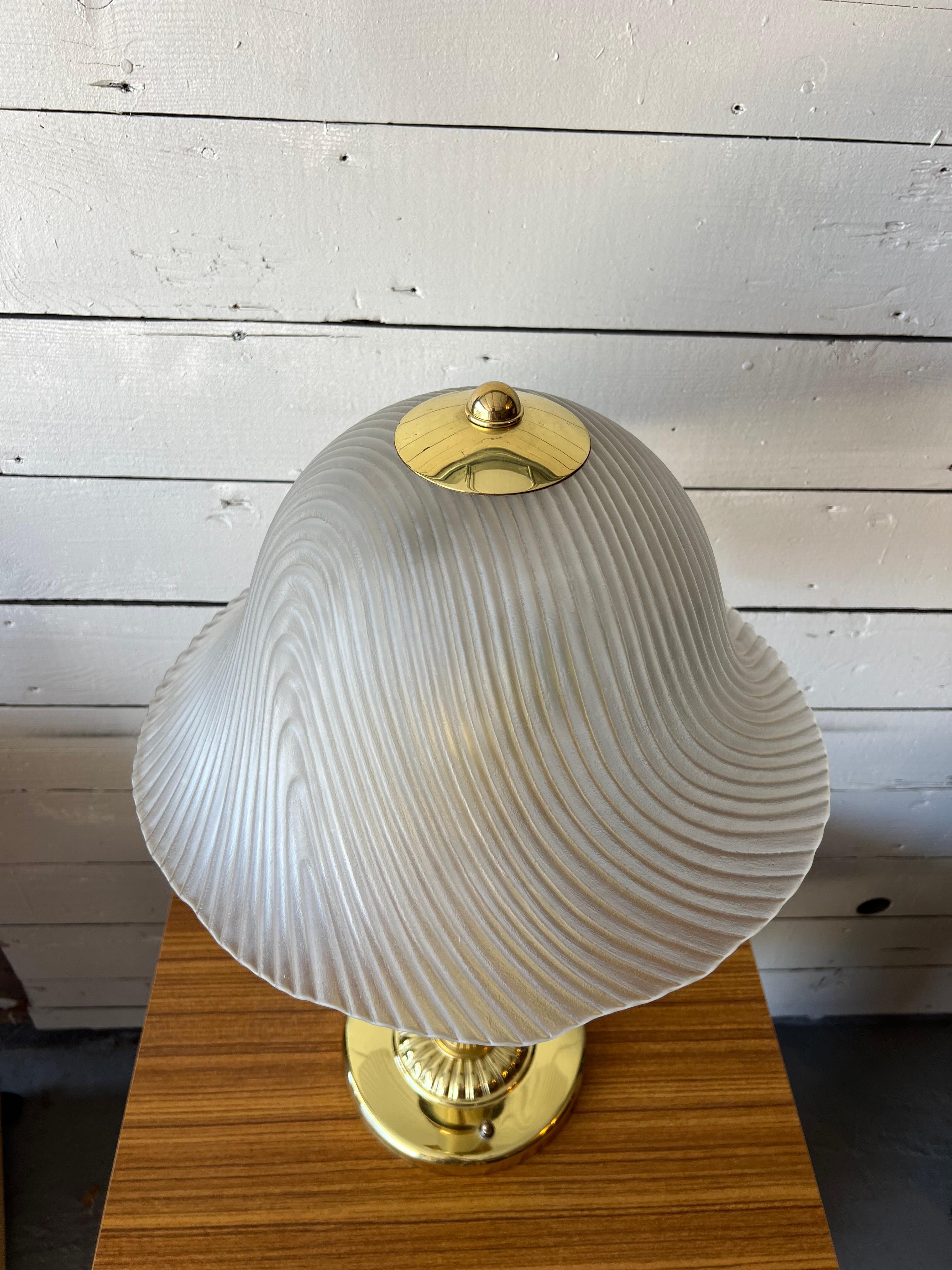 Presenting a gorgeous heavyweight art deco hollywood regency table lamp. Complete with a gold tone weighted base and stem and topped with a curvy, ribbed frosted glass shade. Two bulbs for double the brightness. 

Overall excellent vintage