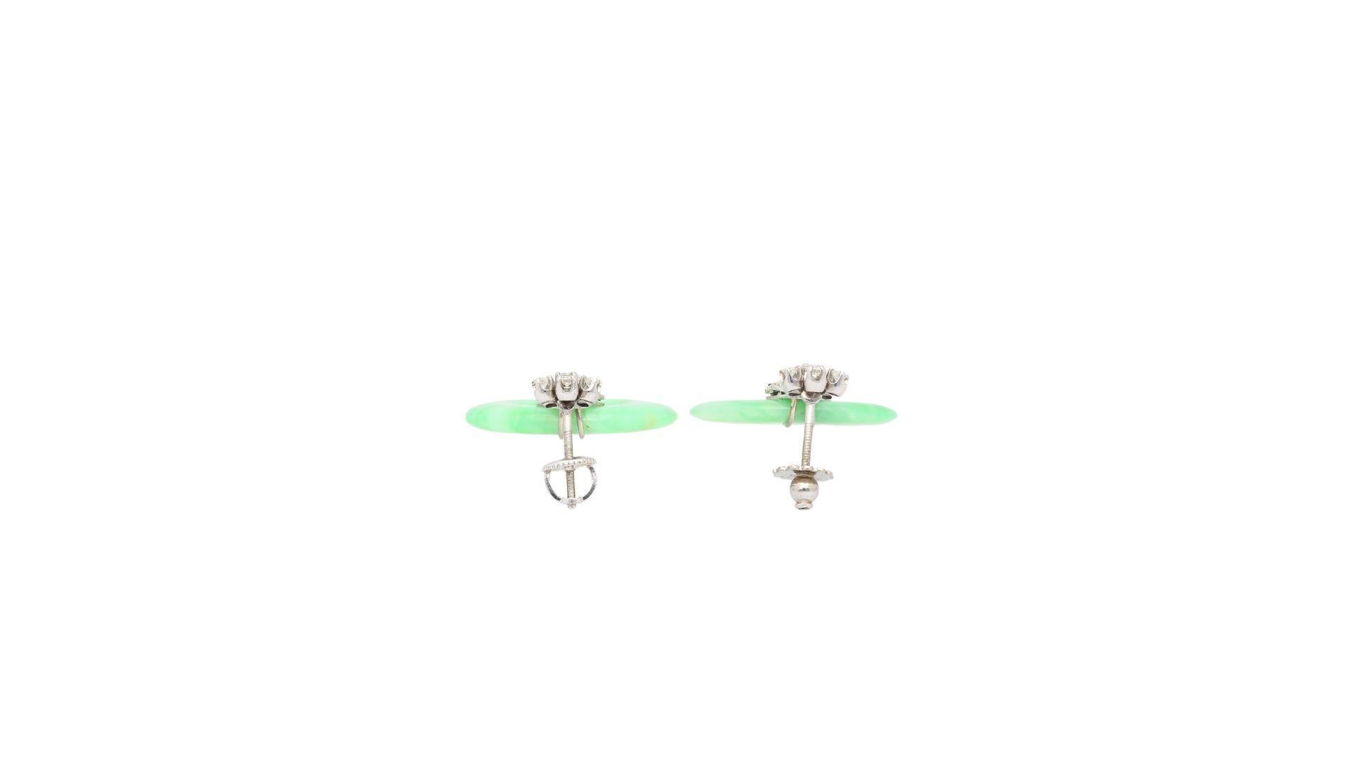 Vintage Jade, Diamond & Sapphire Drop Earrings in 14K White Gold. 

This set of vintage drop earrings features a doughnut-carved natural jadeite jade gemstone. The jade is paired with additional round-cut diamond detailing secured in a prong