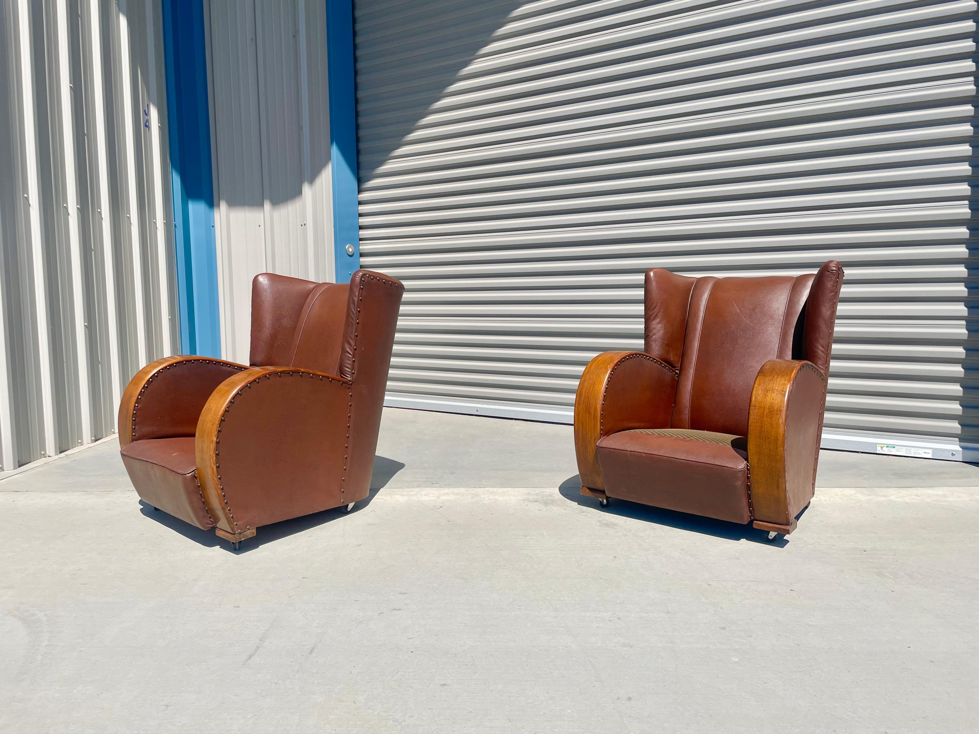 Vintage Art Deco leather lounge chairs manufactured in the United States, circa 1970s. These beautiful lounge chairs feature two-barrel armrests leading down, giving them a tremendously distinctive design for their era. The lounge chairs also