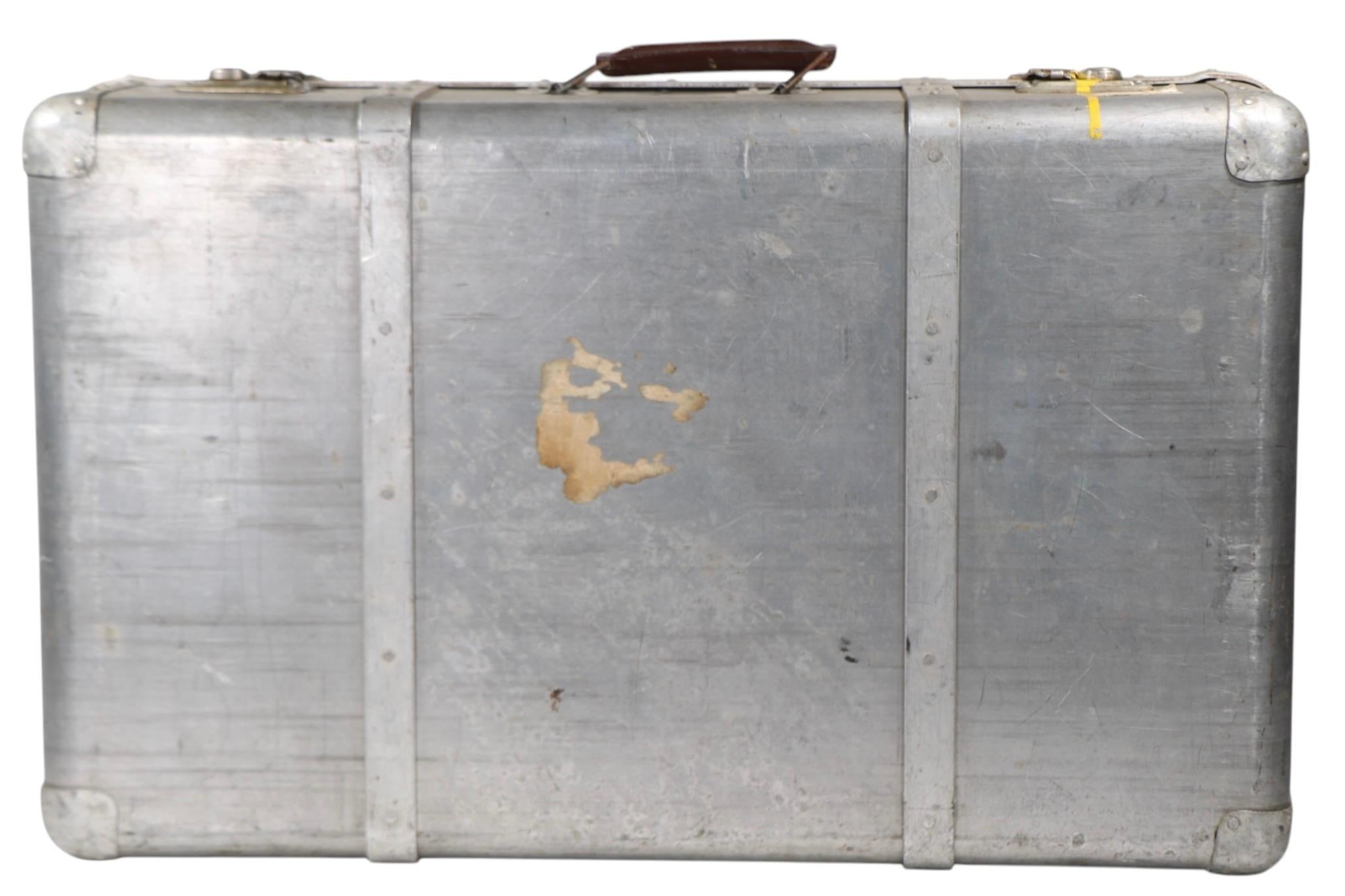 Chic vintage  aluminum luggage, suitcase, circa 1930/60's. The case has a riveted case, with original leather grip handle. This example is in good overall condition, showing cosmetic wear, blemishes, scuffs etc, normal and consistent with age. The