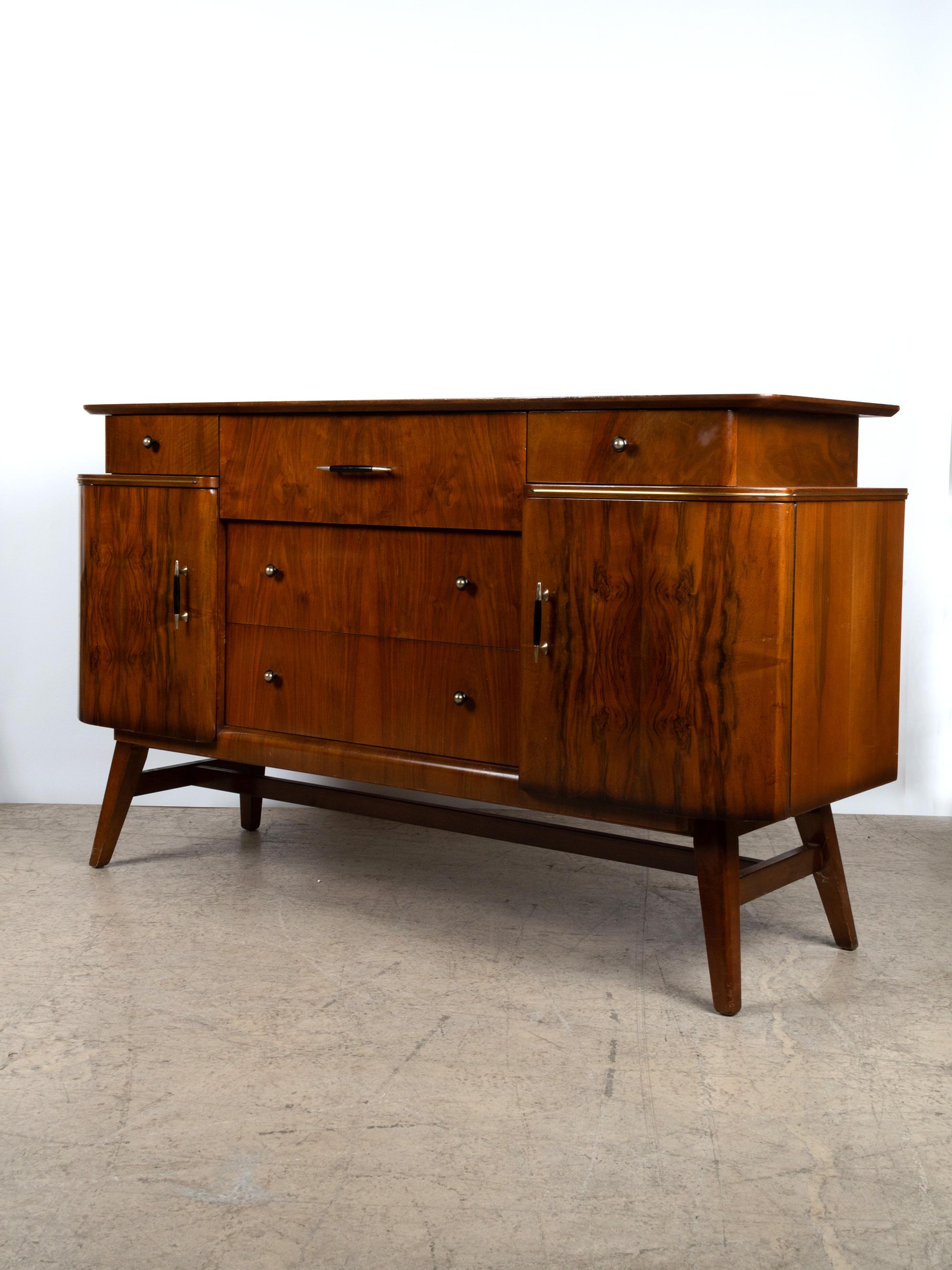 Figured walnut midcentury credenza sideboard by British manufacturer Beautility England, circa 1960. An elegant sculptural piece in the Art Deco manner.
The sideboard is constructed in mahogany and finished in beautiful book matched burr (burl)