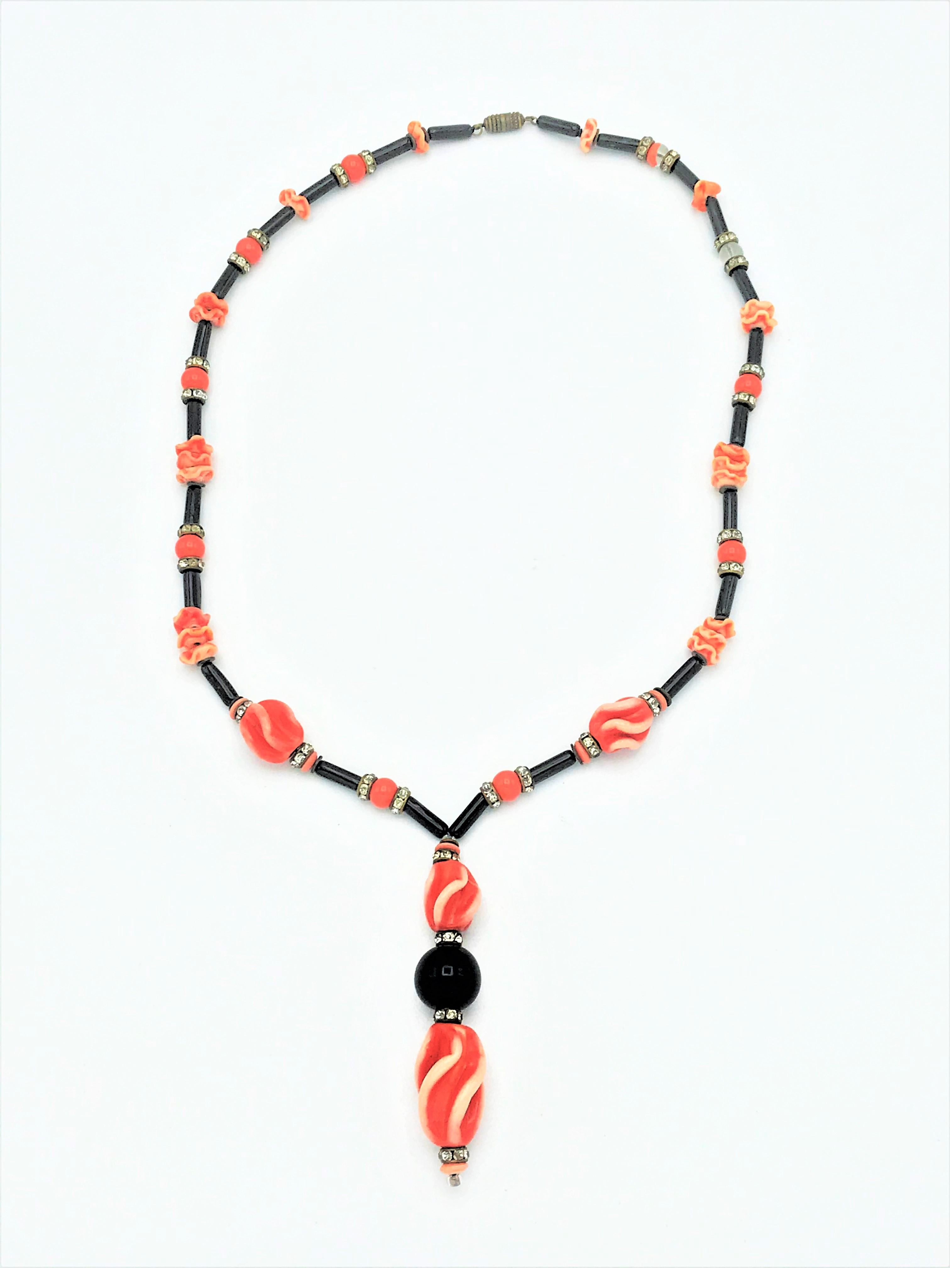 An early deco chain from France, recognizable by the rotary clasp. Consisting of black 1.2 cm long sticks, rhinestone,  rosette ball in orange glass, corrugated glass balls in orange.
The black bow pin is sold separately!
Measurement: Total length