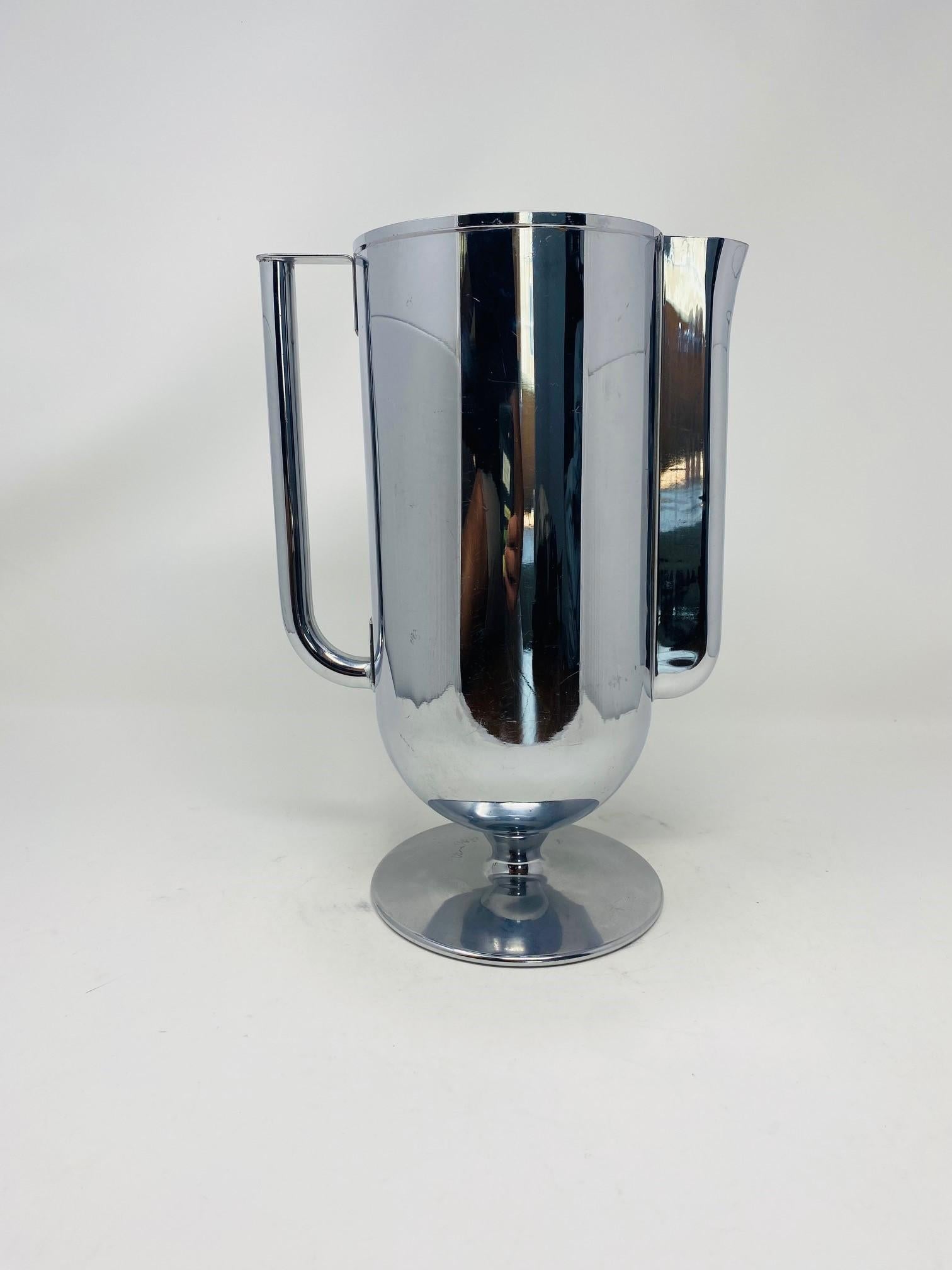 Beautiful art deco chrome pitcher by Norman Bel Geddes.  This beautiful pitcher will bring light and attention to your bar.  Constructed seamlessly and beautifully, this piece elevates your bar style and brings a new level of taste.  Minimal and