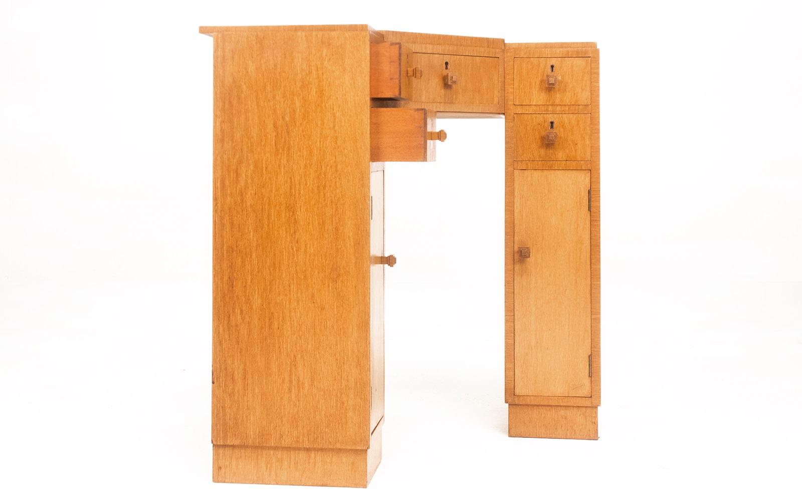Art Deco corner desk

An Art Deco blonde oak corner desk with five drawers and two cupboards. 

The desk is in a stepped form, and the drawer/door handles are moulded to match.

Very much in the manner of Heals & Co.

English, circa 1930.
