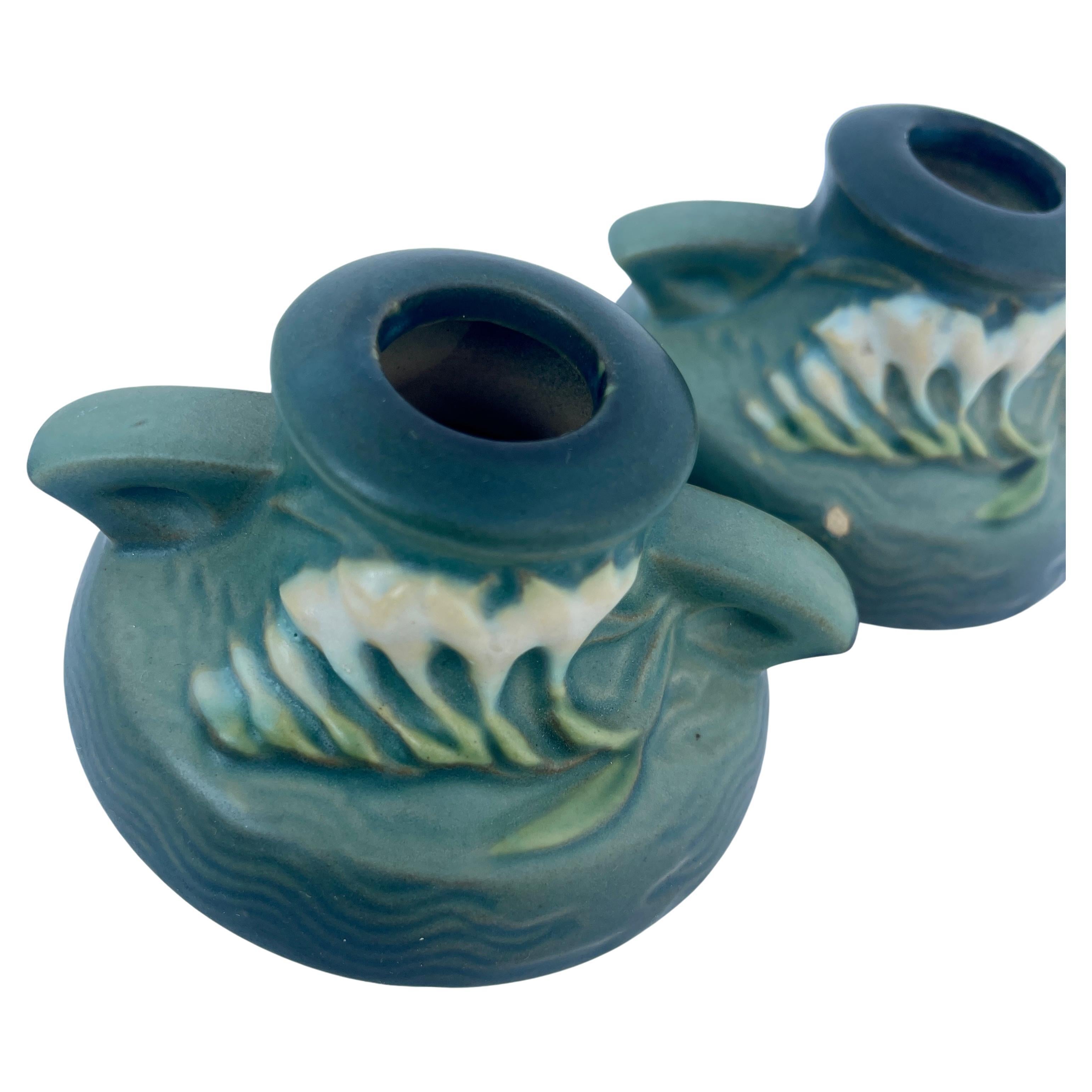 Art Deco Roseville pair of candleholders, circa 1930's. Signed on the underside by the esteemed maker Roseville Pottery company in the United States. The small pair of candleholders are a rich green color with rose and blue accents. Soft dreamy