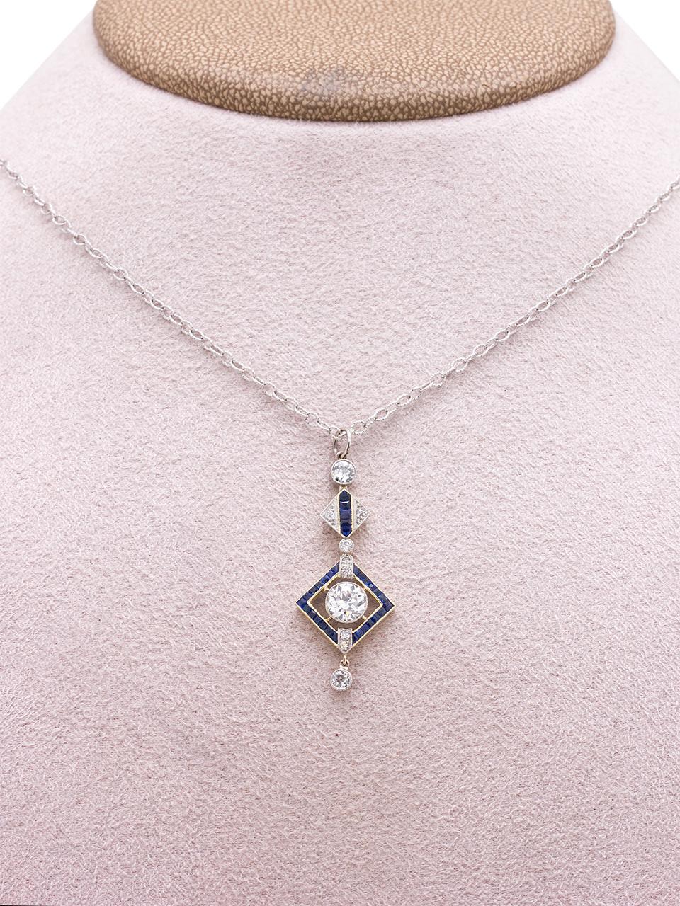 Significant Art Deco elongated platinum pendant, featuring a gorgeously cut 0.85ct Old European Cut center diamond, surrounded by smaller OEC diamonds and bezel-set calibrated blue sapphires. Hinged components allow this lovely piece to move freely