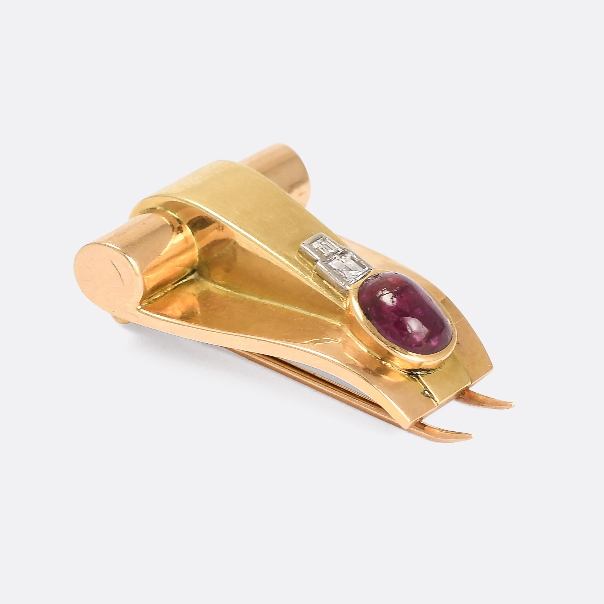 A striking Art Deco brooch set with a natural cabochon ruby and diamond centrepiece. The design is reminscent of a scroll or buckle (I can't quite make up my mind which..) and is very typically Deco in style. It's crafted in 18 karat gold, with