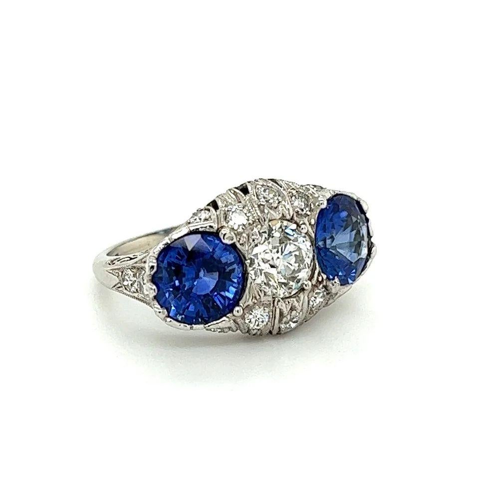 Simply Beautiful! Finely detailed Art Deco Platinum Three Stone Cocktail Ring. Centering a securely nestled Hand set round Blue Sapphire, approx. 1.65 Carat, set on either side with Old European-Cut Diamonds, weighing 0.97 Carat. Either side Hand