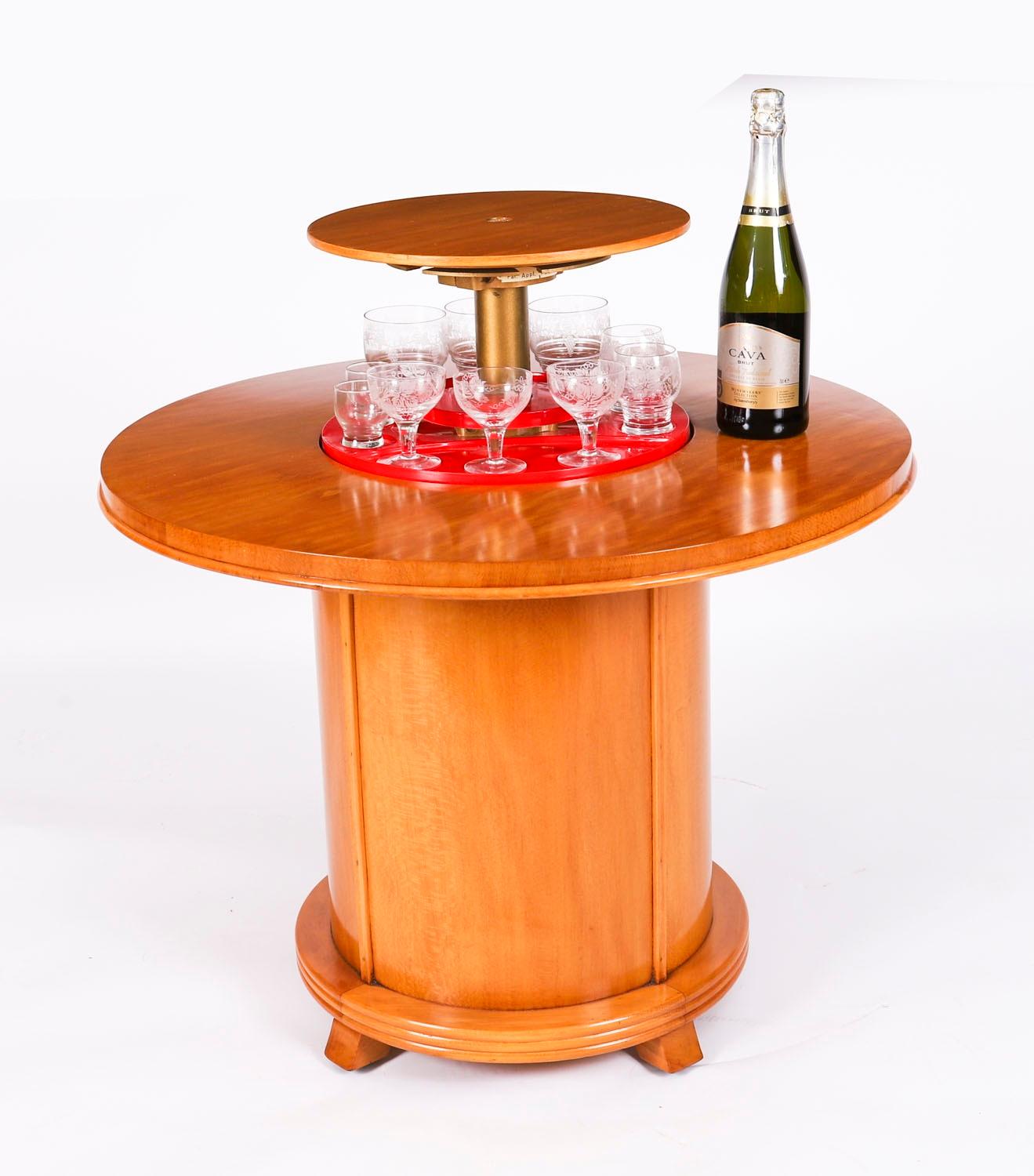 This is a fantastic Vintage English sleek and elegant Modernist satin wood pop up cocktail cabinet with glassware, Circa 1950 in date.

It is of architectural form, made in figured satinwood, and comprises a circular top with a central circular pop