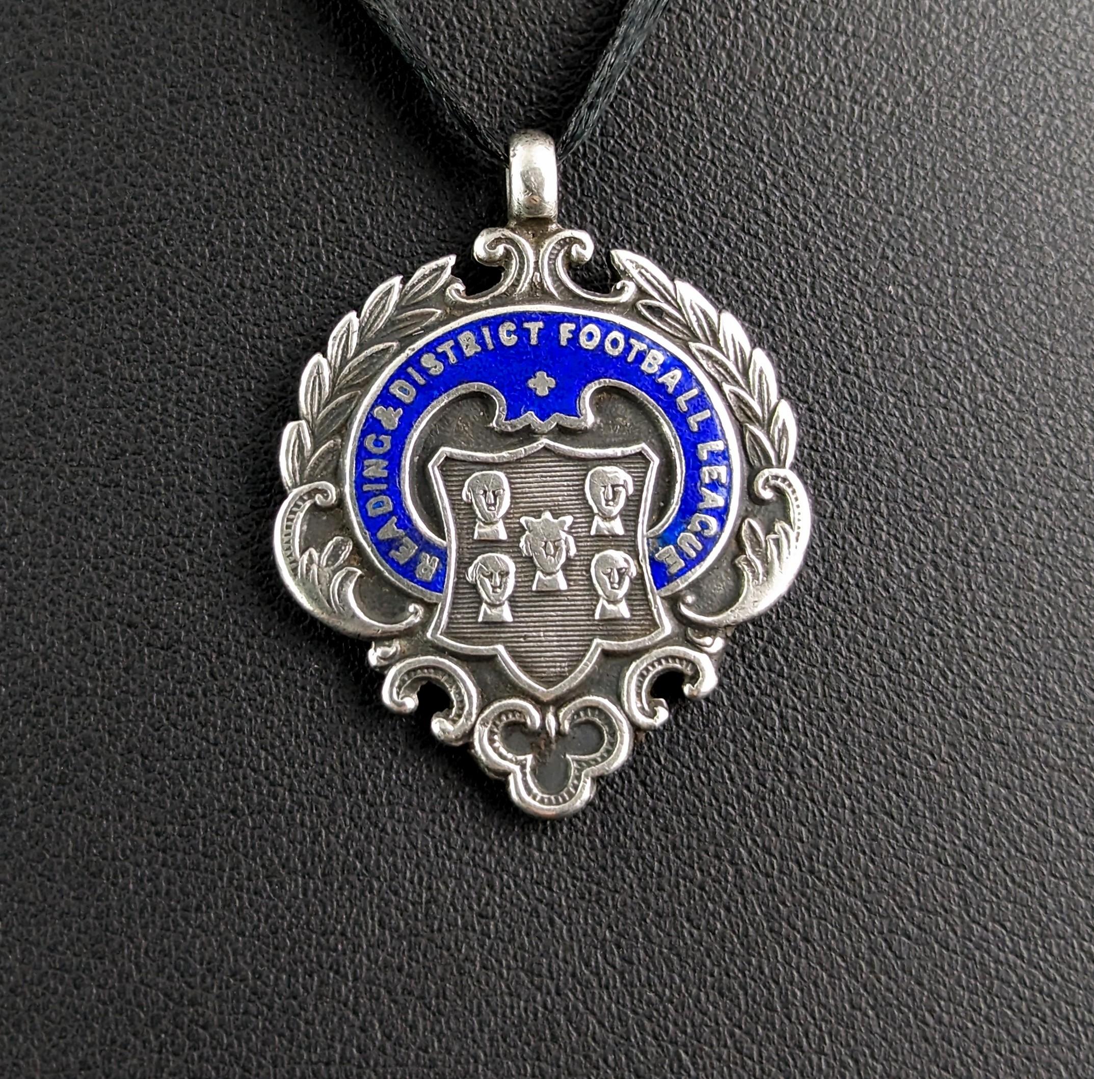 An attractive antique sterling silver and cobalt blue enamelled fob pendant.

It is an unusual shaped fob with a wreath surrounding the outer rim and a club at the bottom, the centre of the fob has a number of faces in light relief contained within