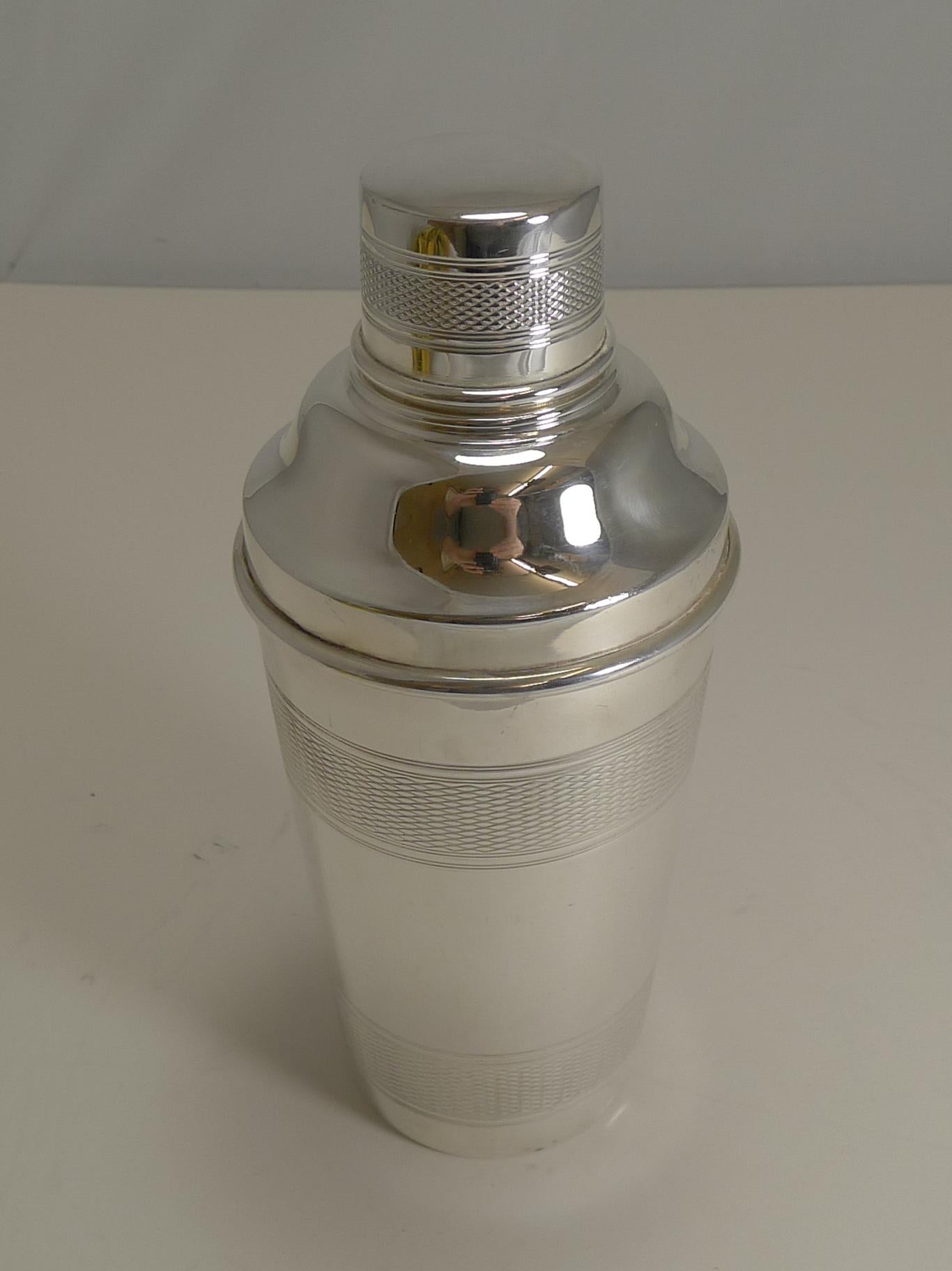 A handsome vintage silver plated cocktail shaker with engine-turned decoration.

The underside is signed by the silversmith P.H. Vogel and Co., and is marked 