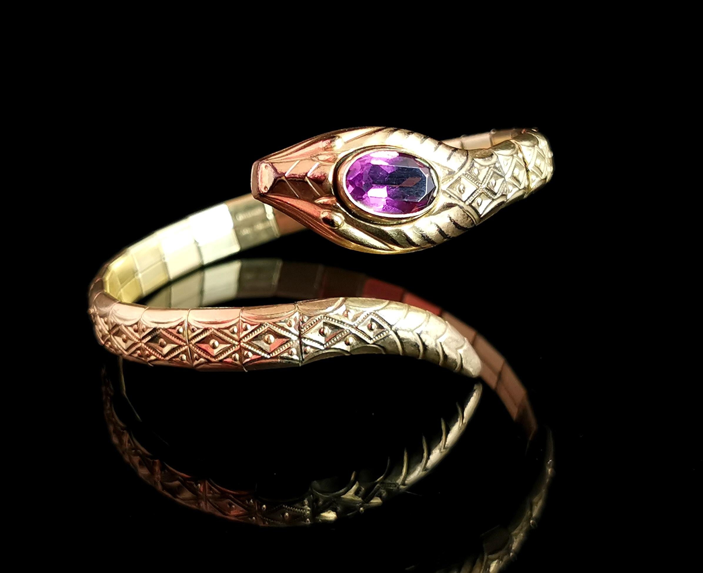 An amazing vintage, Art Deco snake bangle.

This gorgeous bangle is designed as a coiled snake in a rich rolled yellow gold with a textured and embossed body.

The head if the snake is set with a large Amethyst paste stone in rich purple.

The