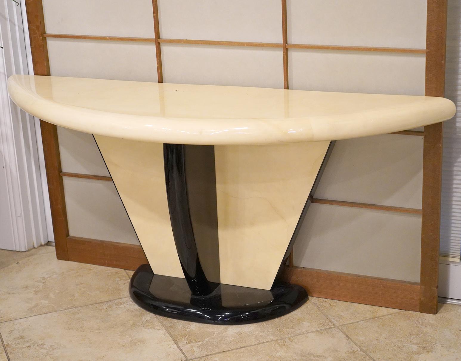 The striking design of this Art Deco inspired Karl Springer style demilune console table combines the warm and nuanced surfaces of lacquered goatskin parchment with high gloss ebonized structural elements. Perfect craftsmanship adds to the
