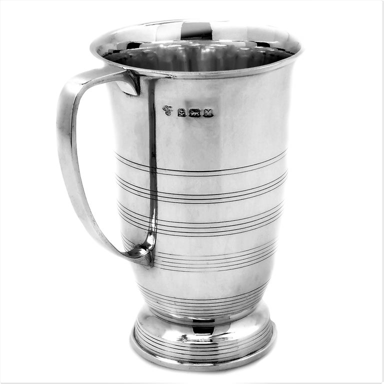 An Art Deco solid Silver Mug in an elegant, understated design. The body of the Mug is in plain polished silver with engraved reeded bands around the body and the foot of the Mug.

Made in Birmingham in 1936 by Sir Richard Woodman Burbidge (The
