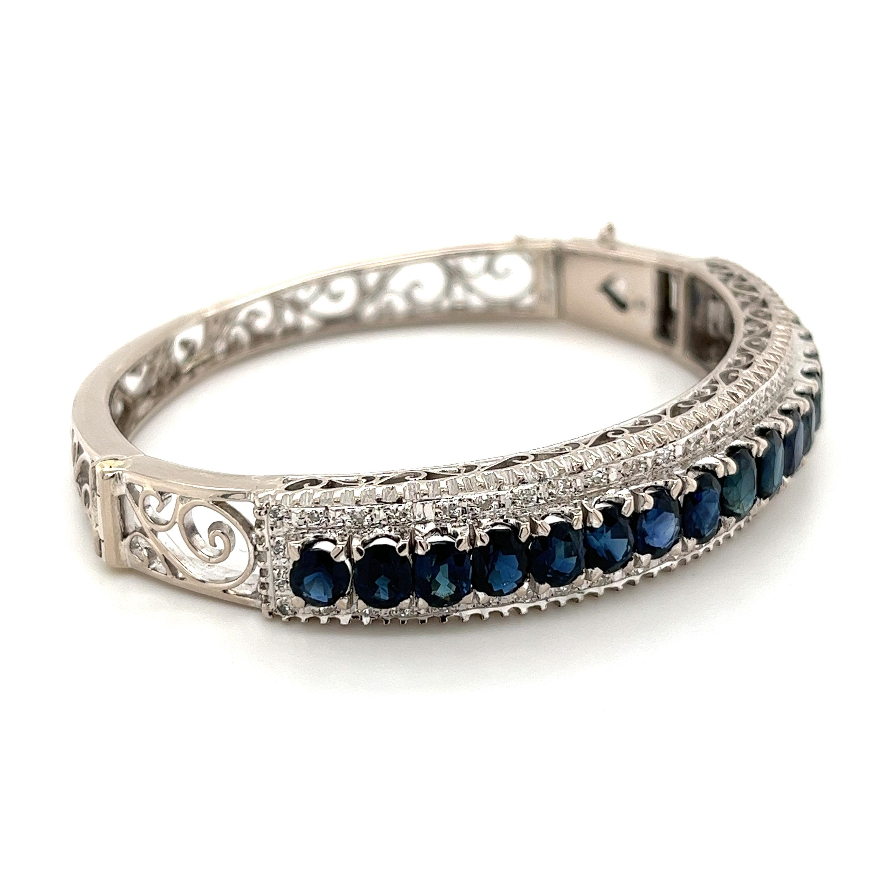 Vintage, Art Deco-inspired, Blue Sapphire bangle in 14 karat solid white gold. Consistent with the iconic symmetrical design pattern of this historical period of art, jewelry, and design.

Each lustrous Blue Sapphire is handset with meticulous