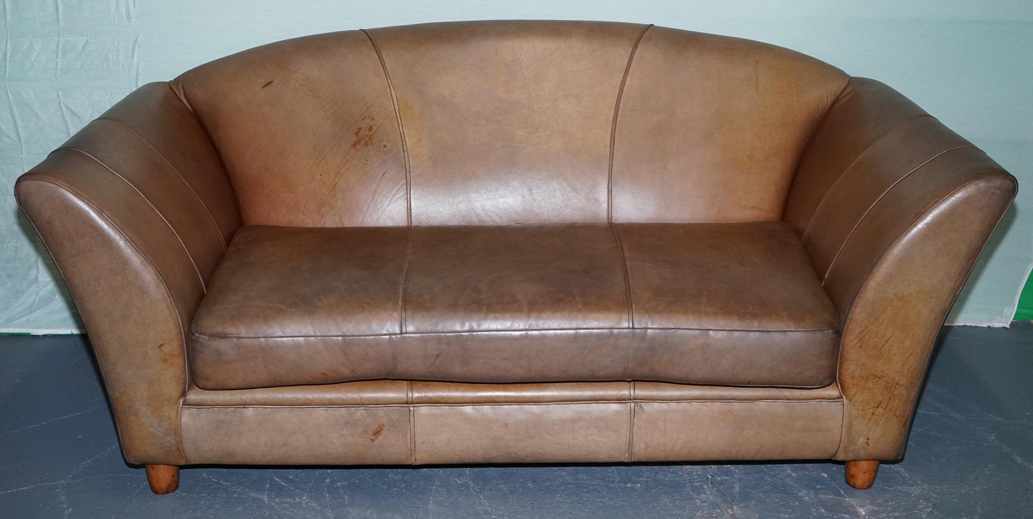 
Antiquariato di Londra



Questo divano in pelle di ispirazione Art Deco vintage emana uno stile e un comfort senza tempo. Rivestita in pelle marrone invecchiata con una patina naturale, combina braccioli curvi, uno schienale smerlato e un profondo