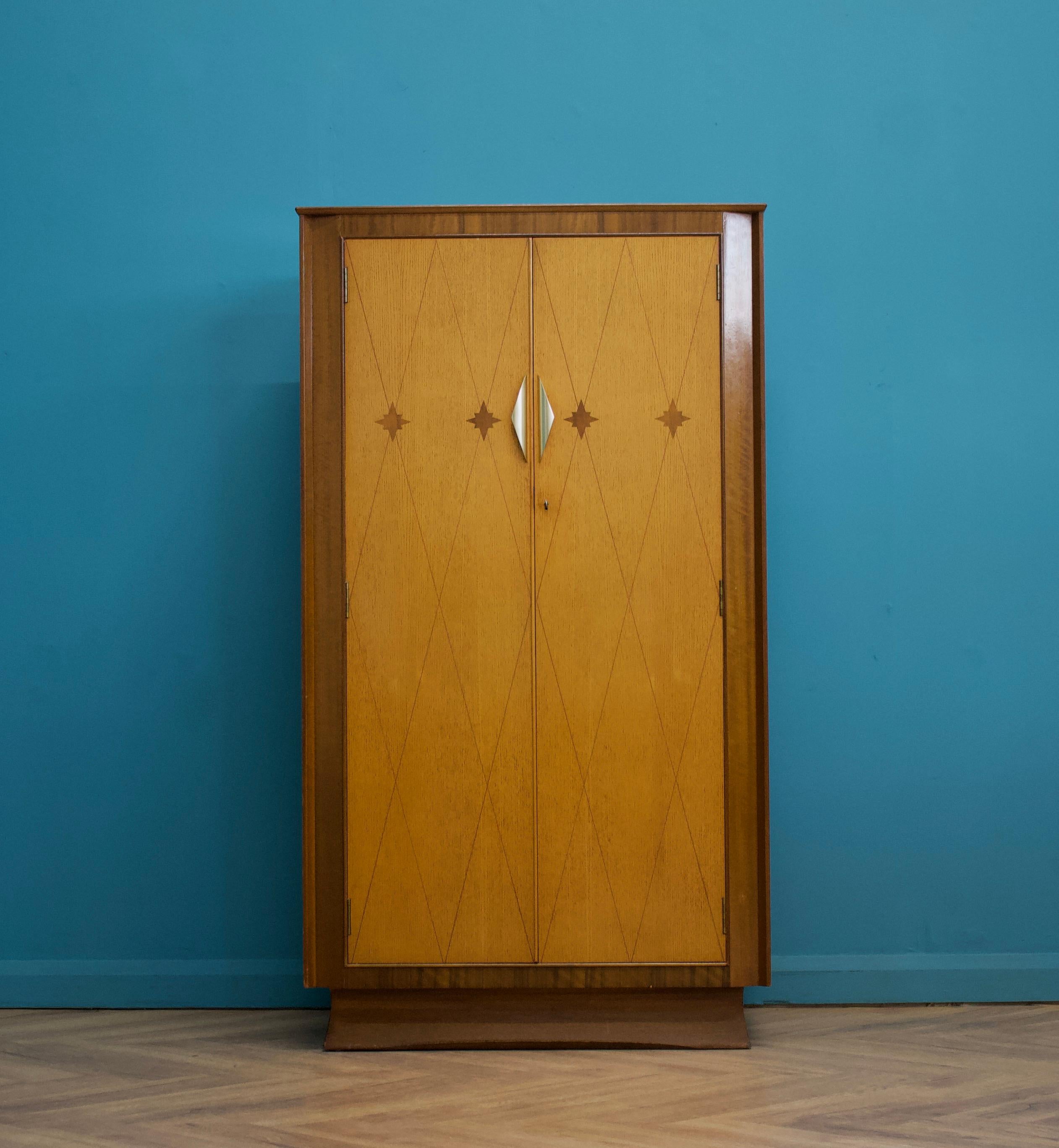 A mid century walnut and oak Art Deco style compactum / compact wardrobe from Harris Lebus - circa 1950's


This piece has beautiful inlays to the doors
Featuring brass handles 


Inside is fitted out with shelves to one side and a rail to the other