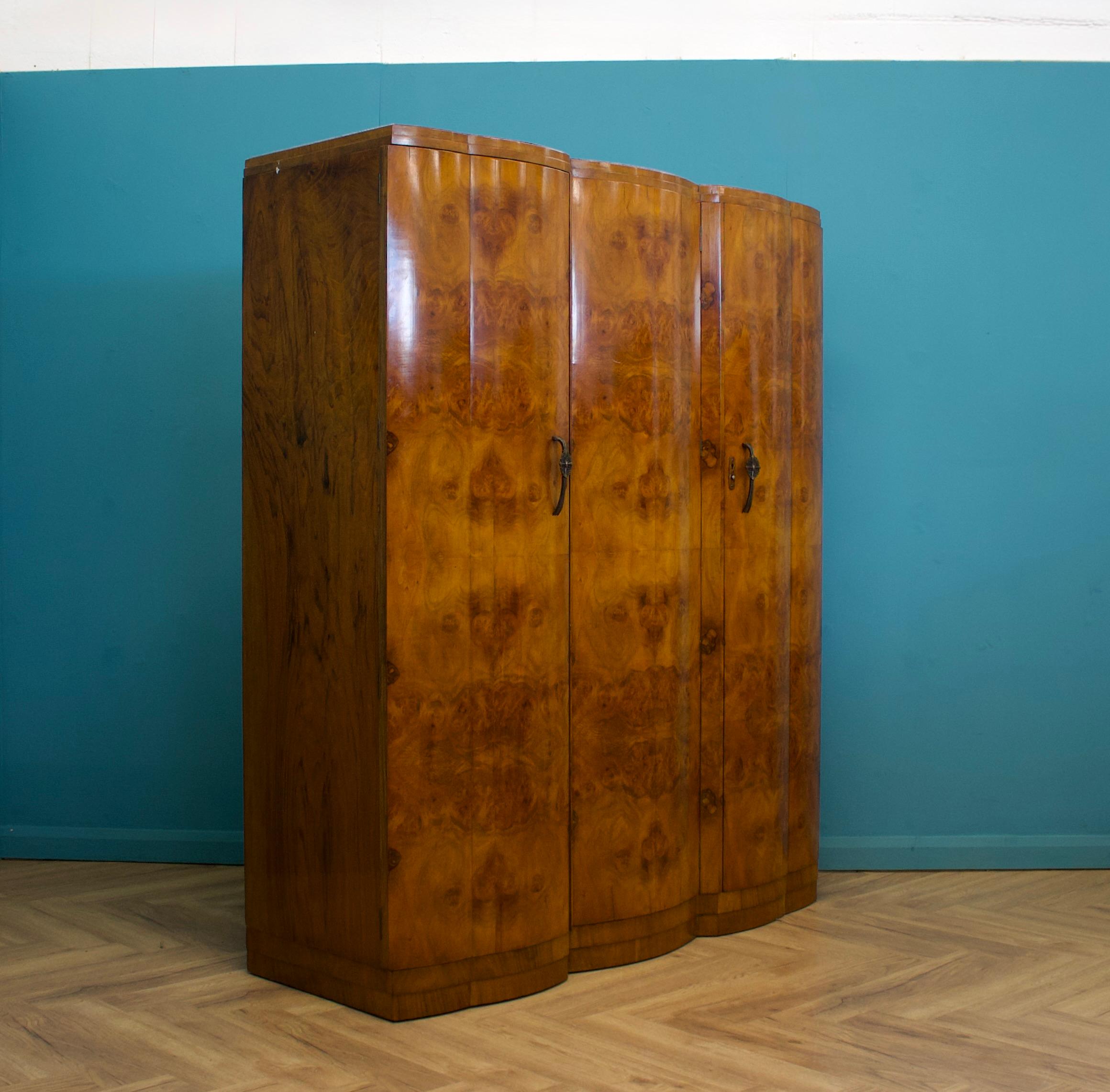 An Art Deco style walnut wardrobe  - circa 1950's -
With an beautifully fitted out interior for plenty of storage.
There's a hanging rail, a pull out hanging rail, shelves, drawers and glass fronted compartments.


Featuring decorative metal
The