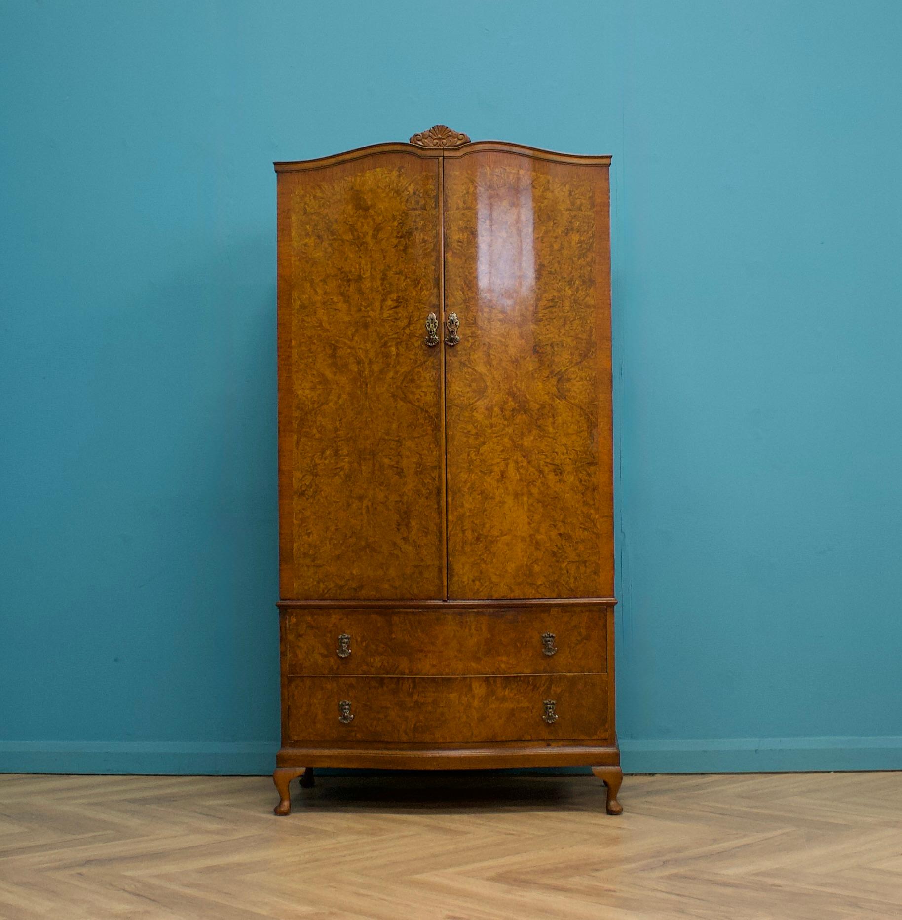 Questo armadio in legno di noce in stile Art Déco, risalente agli anni '50 circa, vanta un interno ben arredato e un ampio spazio di archiviazione per le sue dimensioni compatte. Include un appendiabiti estraibile, ripiani e due cassetti aggiuntivi