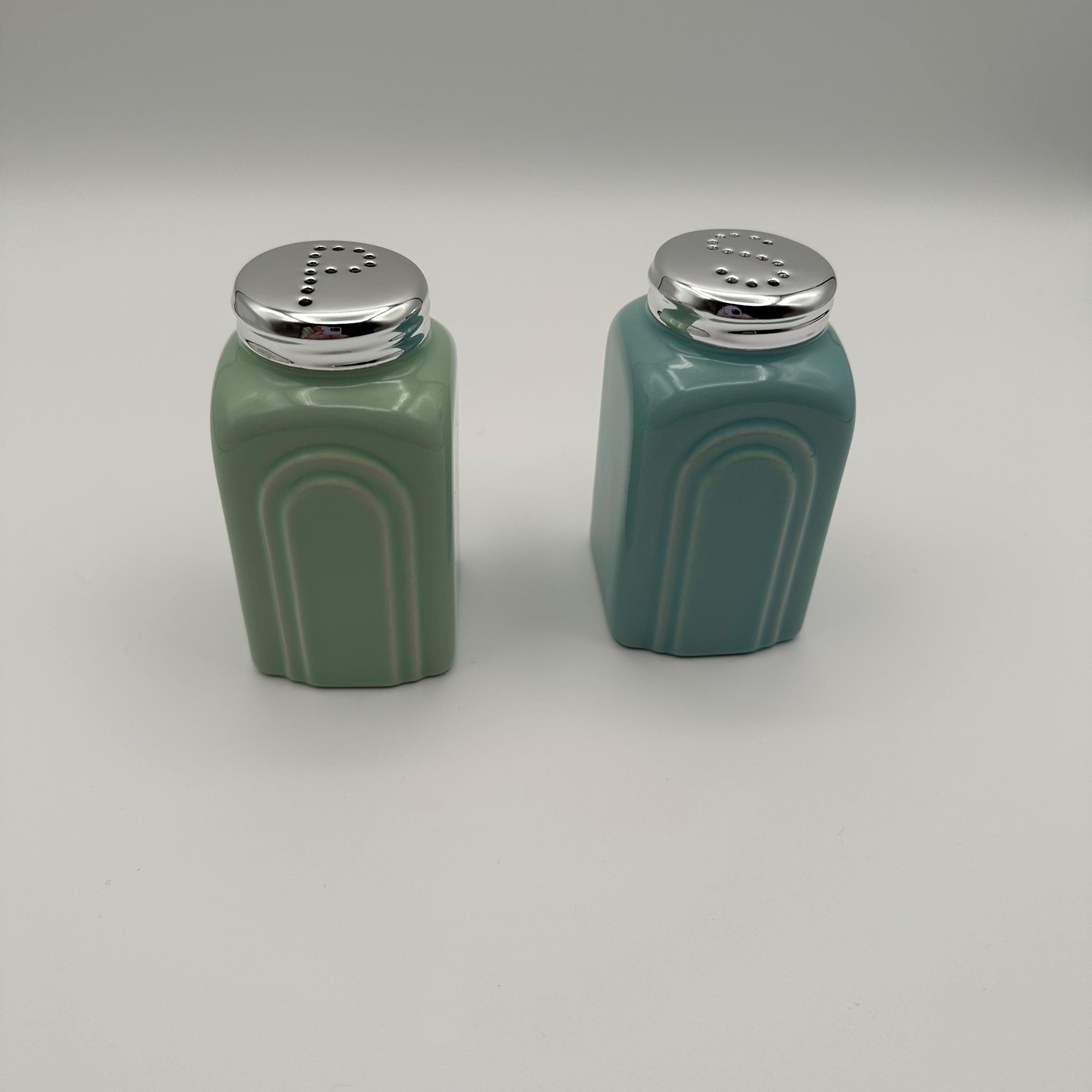 Vintage Art Deco Style Ceramic Salt and Pepper Shakers. A pair glazed in coordinating tones of blue and green. Featuring an art deco style layered arching motif on opposing sides. Stylized holes on the aluminum top pierced in the shape of 