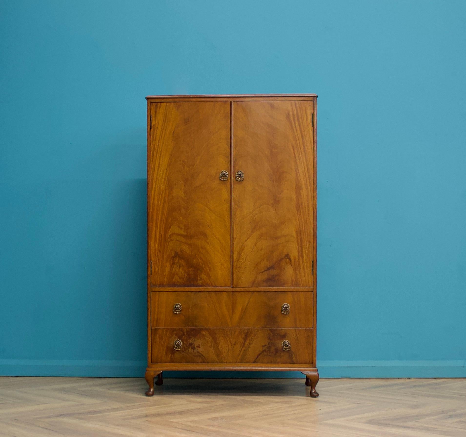 An Art Deco style mahogany compact wardrobe, circa 1950s
Featuring a cupboard with shelves and a hanging rail
To the outside there are two drawers


The piece stands on Queen Anne style feet

The matching dressing table and full size wardrobe is