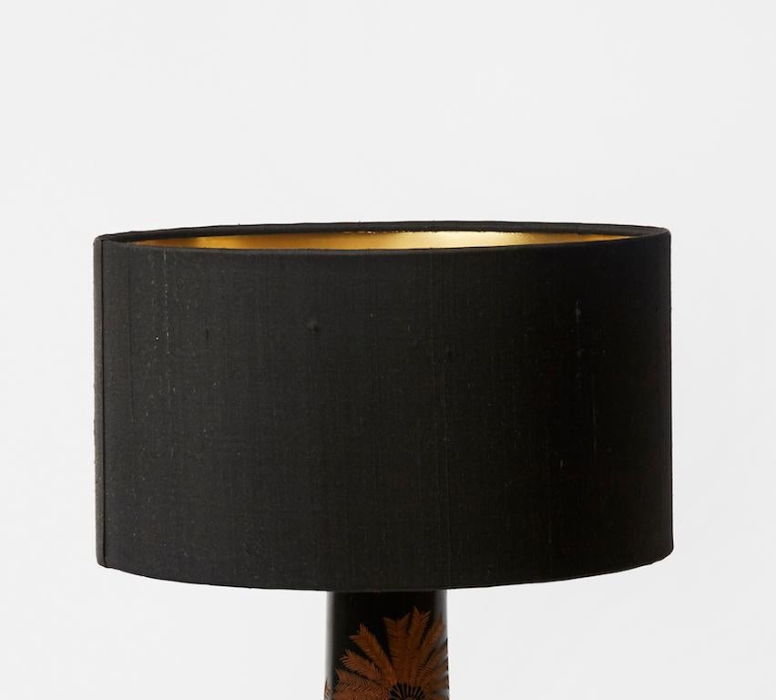 A vintage Art Deco style table lamp with brass base and a raw silk custom black shade. The carved wood stand is engraved with palm tree motifs. Condition and wear consistent with age and use.

Measures: Shade
D 30 cm x H 17 cm
D 11.81 in x H