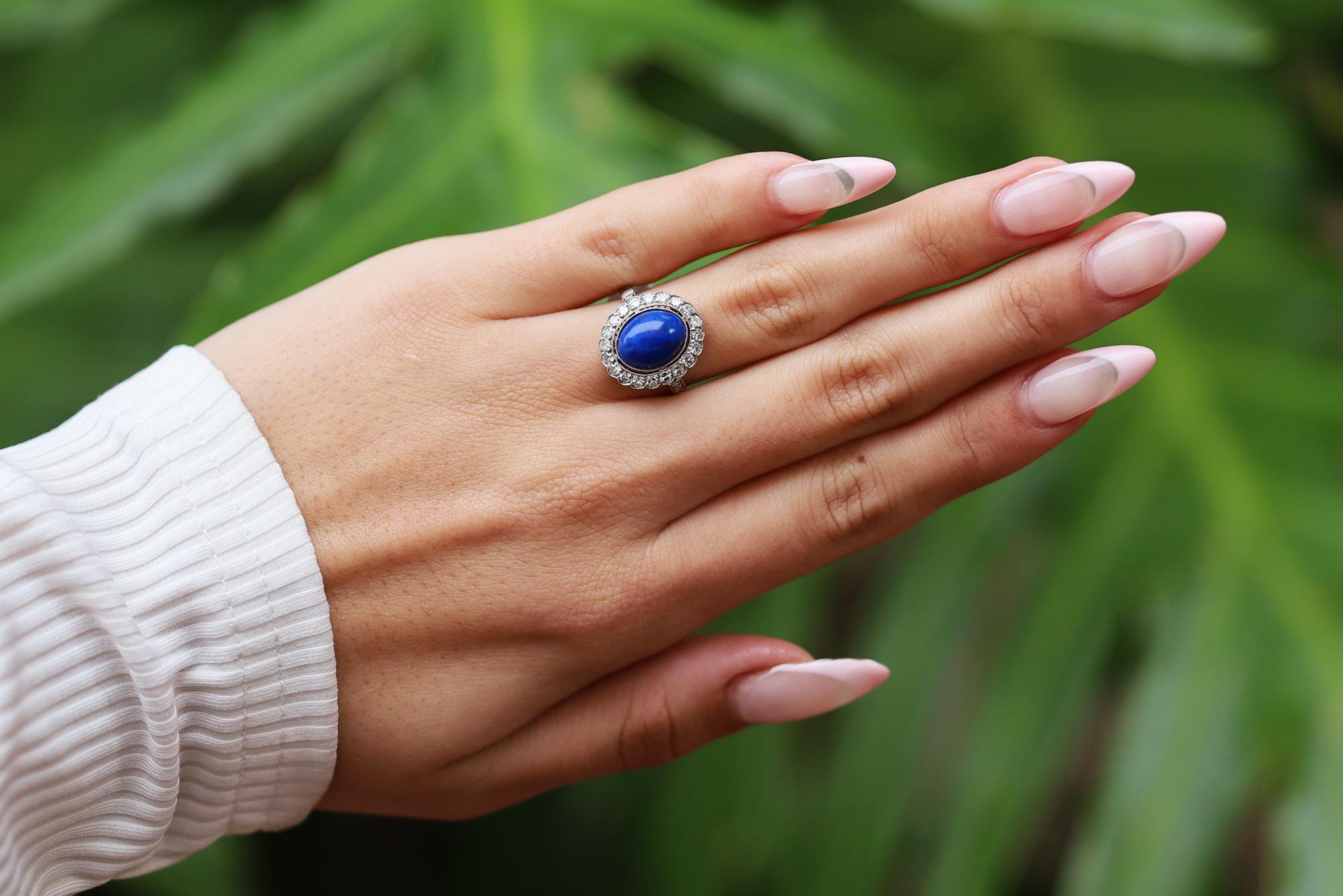 A vibrant, lovely and lustrous Lapis Lazuli gemstone of a pure cobalt blue commands your attention in this non-traditional engagement ring. Encircled by a scalloped platinum halo of sparkling round diamonds along with a divinely filigreed under