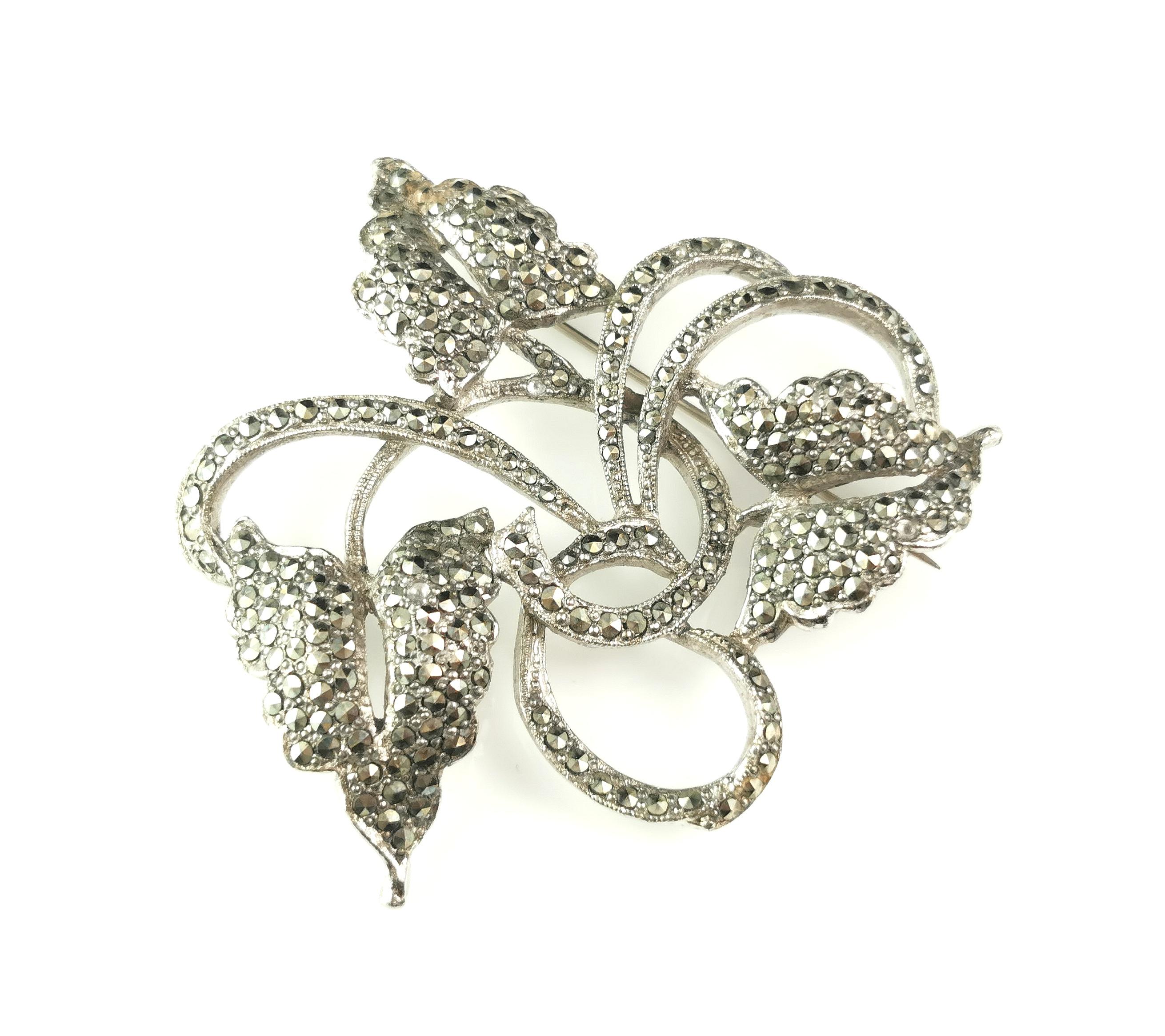 A beautiful vintage marcasite leaf and vine brooch.

This is a larger sized brooch in a leaf and vine design, crafted in silver plated steel and adorned with marcasite stones.

It has a safety style catch and pin fastener.

Unmarked