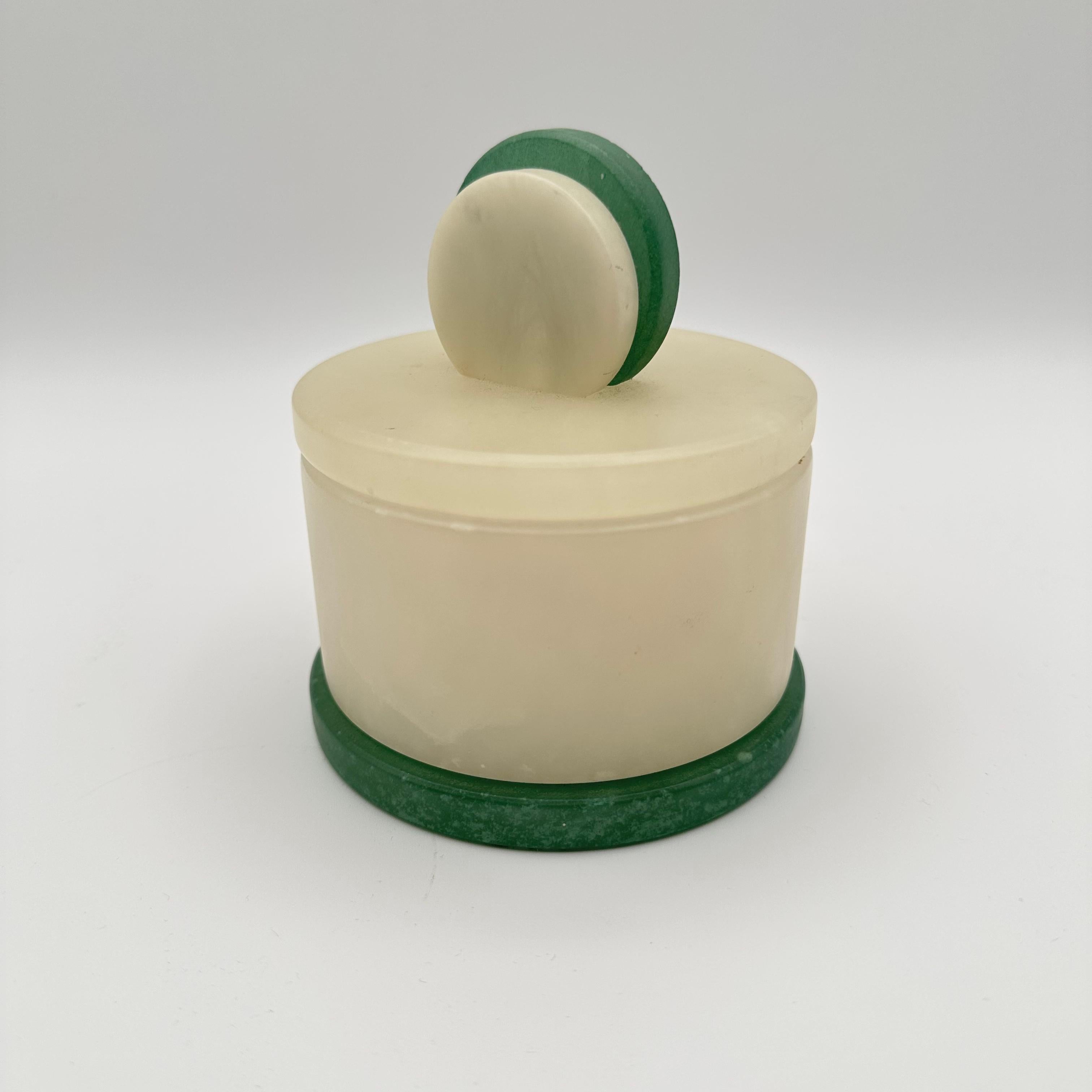 Beautiful round box with two - tone white and green stone design. Likely alabaster. Featuring a two - piece design with unattached lid, topped with a concentric circle pull. Thick green base. Some black veining throughout the white stone. 
