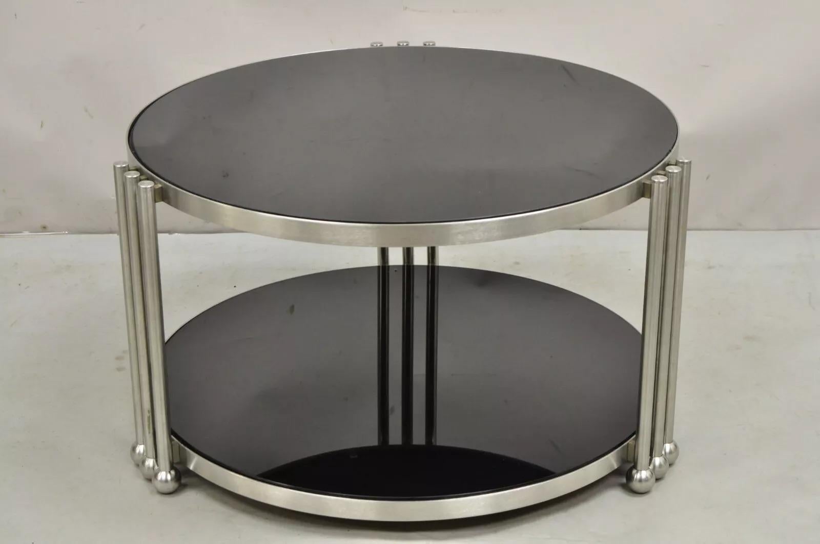 Vintage Art Deco Stil Stahl und Rauchglas 2 Tier Runde Couchtisch. Der Artikel verfügt über 2 Etagen aus Rauchglas mit schwarzer Stoffunterseite, kugelförmige Füße und klare Art-Déco-Linien. CIRCA Spätes 20. Jahrhundert. Abmessungen: 17