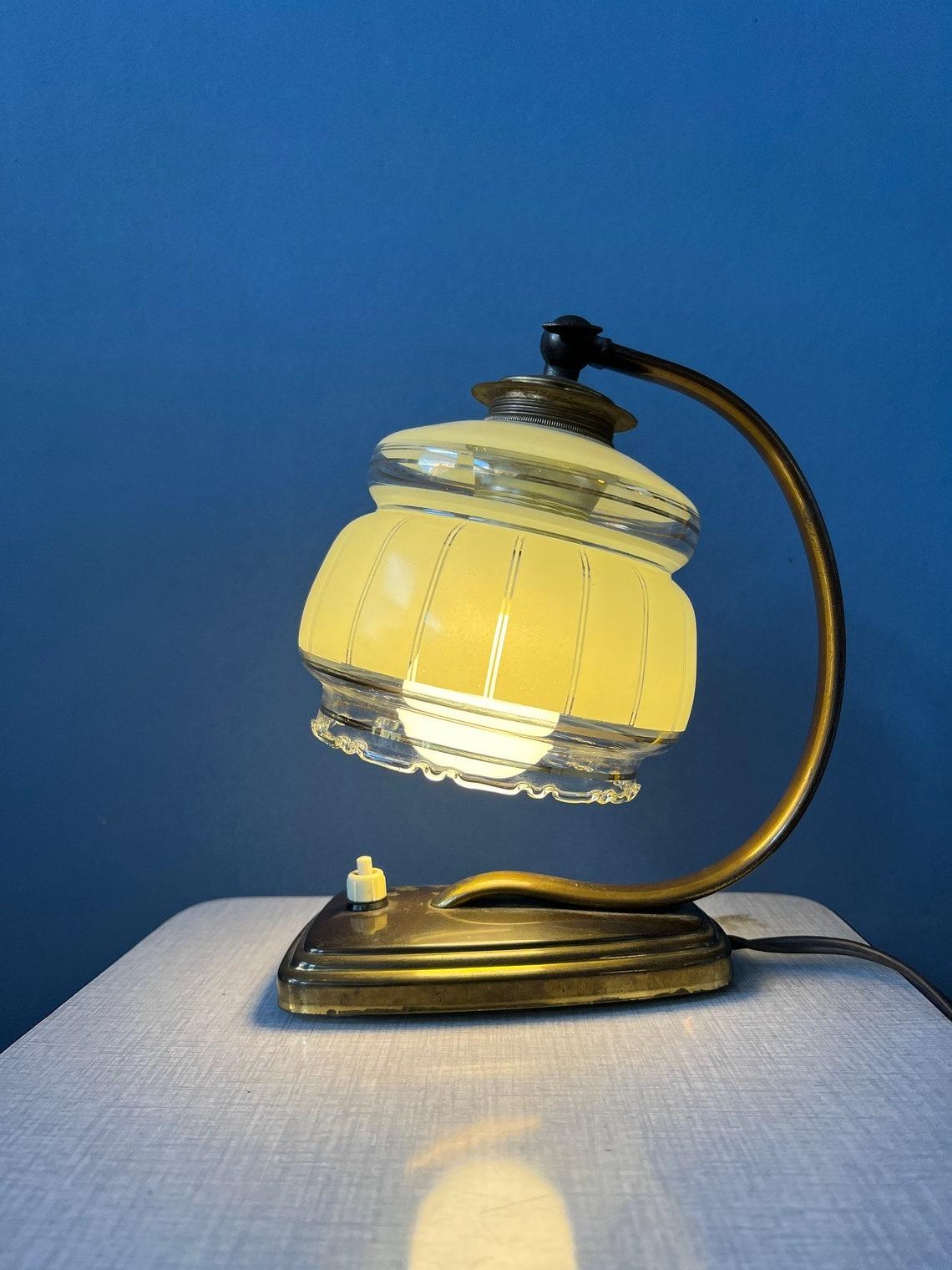 Art deco bedside table lamp with glass shade. The lamp has a bronze-coloured base and a glass shade. The lamp requires an E14 lightbulb and currently has an EU-plug.

Additional information:
Materials: Glass, metal
Period: 1970s
Dimensions: ø Shade: