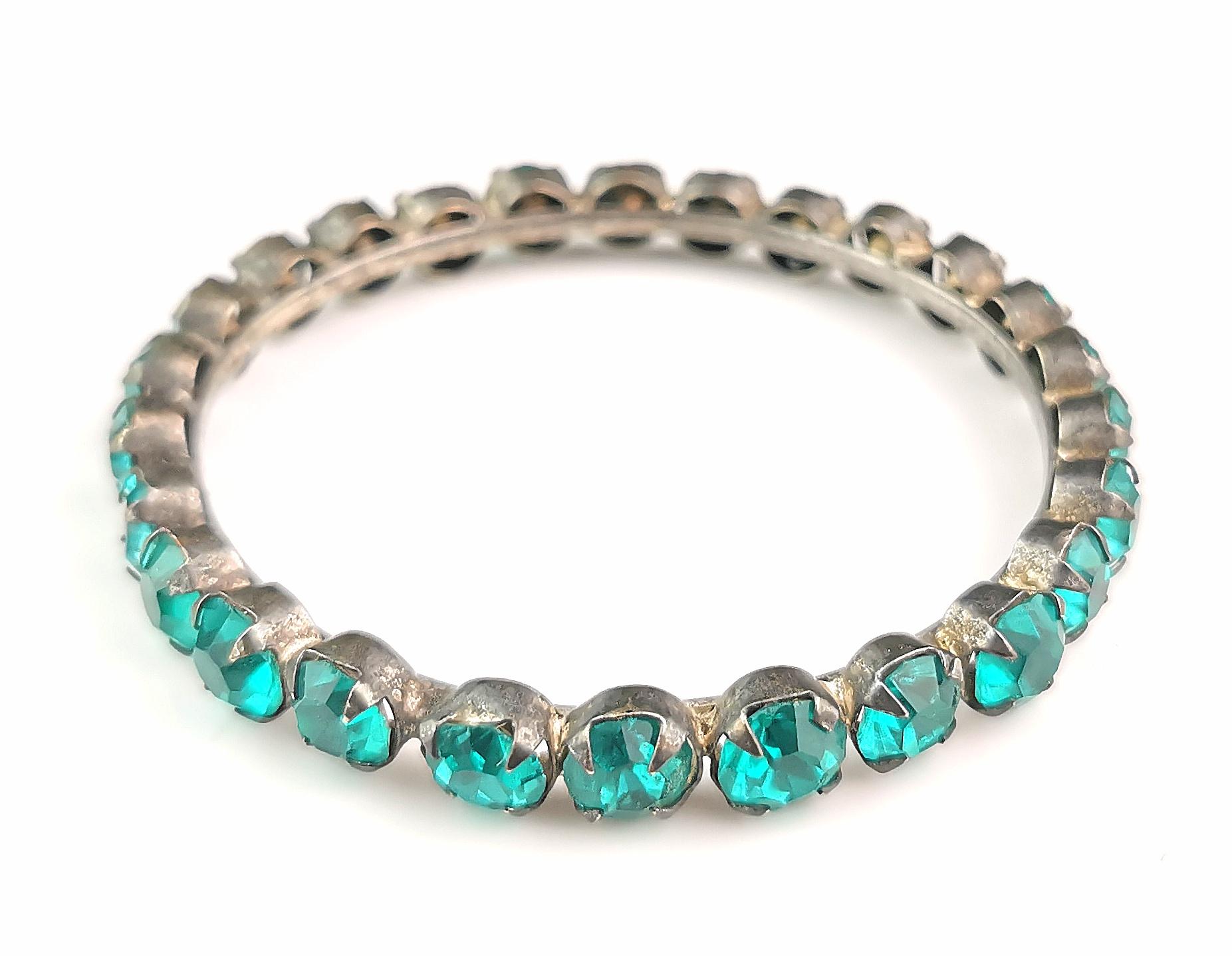 A gorgeous and striking vintage Art Deco era teal blue Paste bangle.

It is made from white metal and is a large size bangle, it is set all around the outside with lovely vibrant teal blue Paste stones, a lagoon blue with a tiny hint of green, they