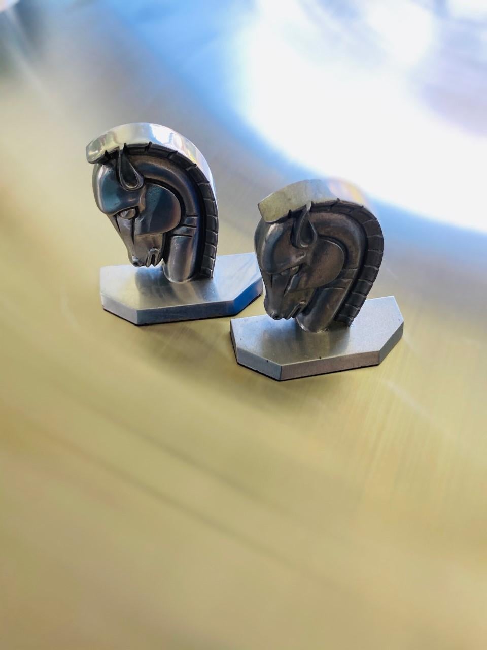 Beautifully classic Art Deco Trojan horse head bookends. This pair is in great vintage condition. Made of steel, these pieces reflect the precise and boldly delineated design characteristic of the Art Deco era. The horse heads are depicted in a