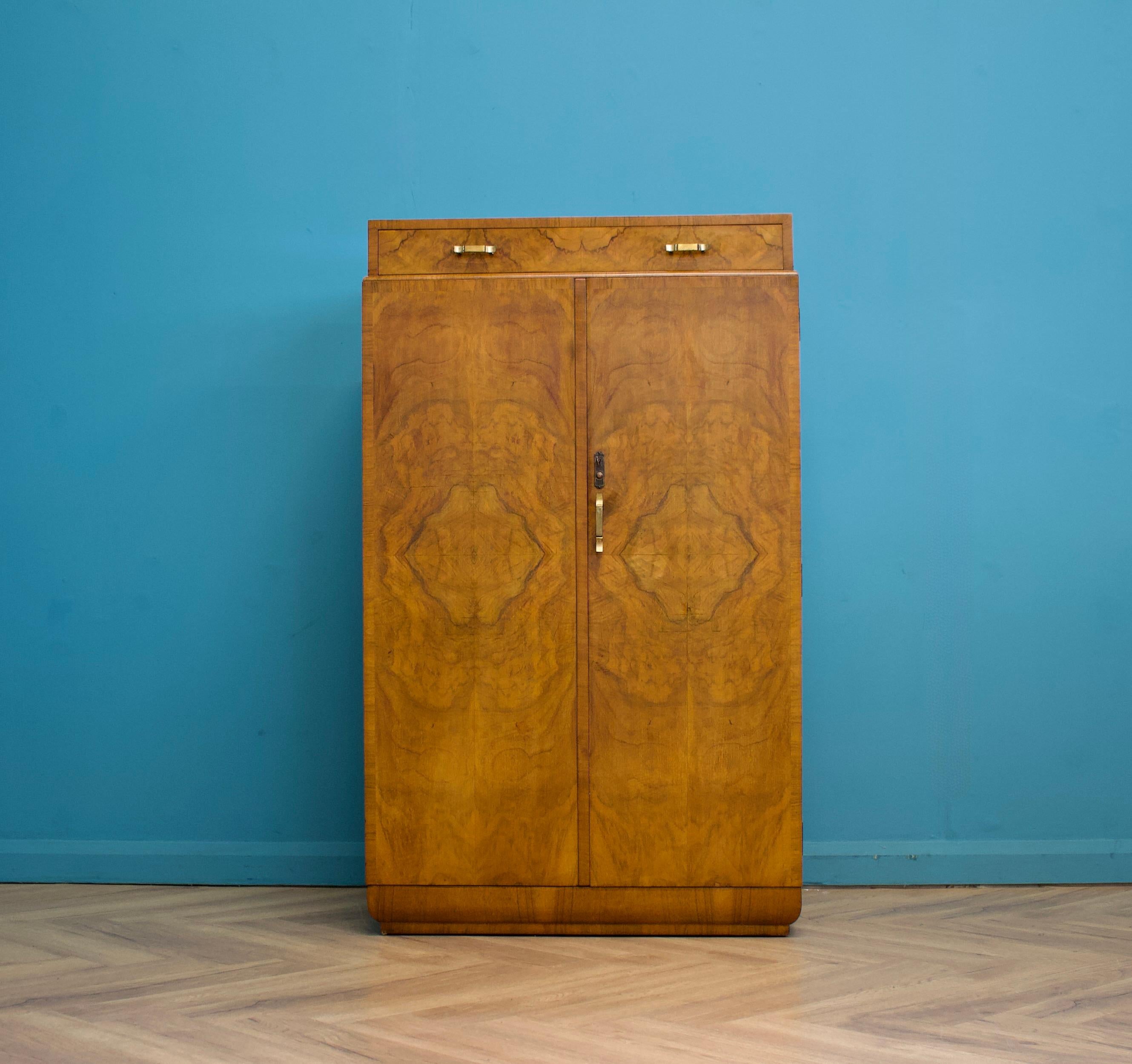 An impressive quality Art Deco burr walnut compactum, circa 1930s

There's drawer to the top and in the cupboard is a pull out hang rail and shelves

The original key is present and the lock works - the handles are made from metal

There's a