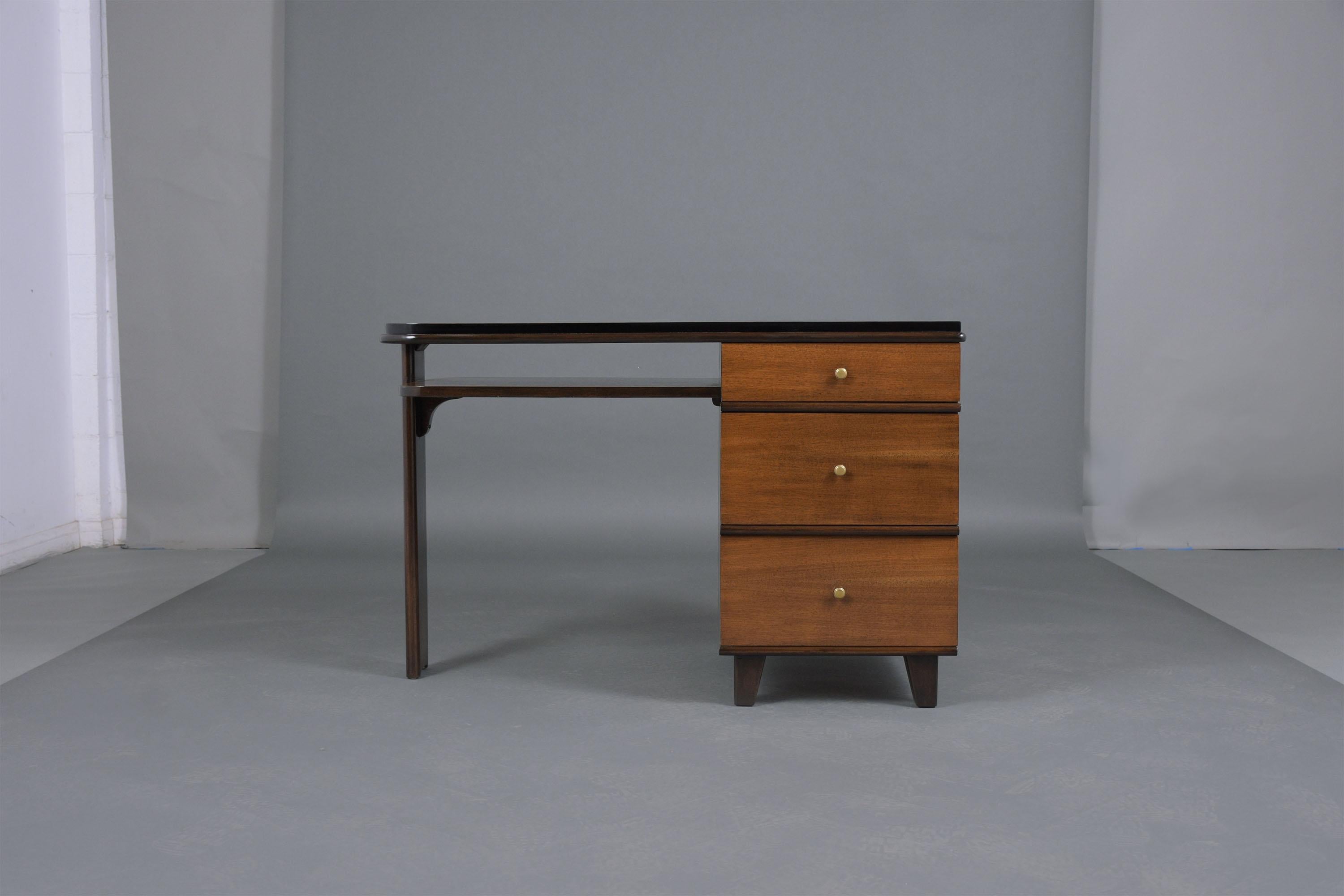 Immerse yourself in the elegance of the past with our 1950s Art Deco Pedestal Desk, a perfect blend of historical charm and modern restoration. This piece has been expertly crafted from wood and professionally restored by our team of skilled