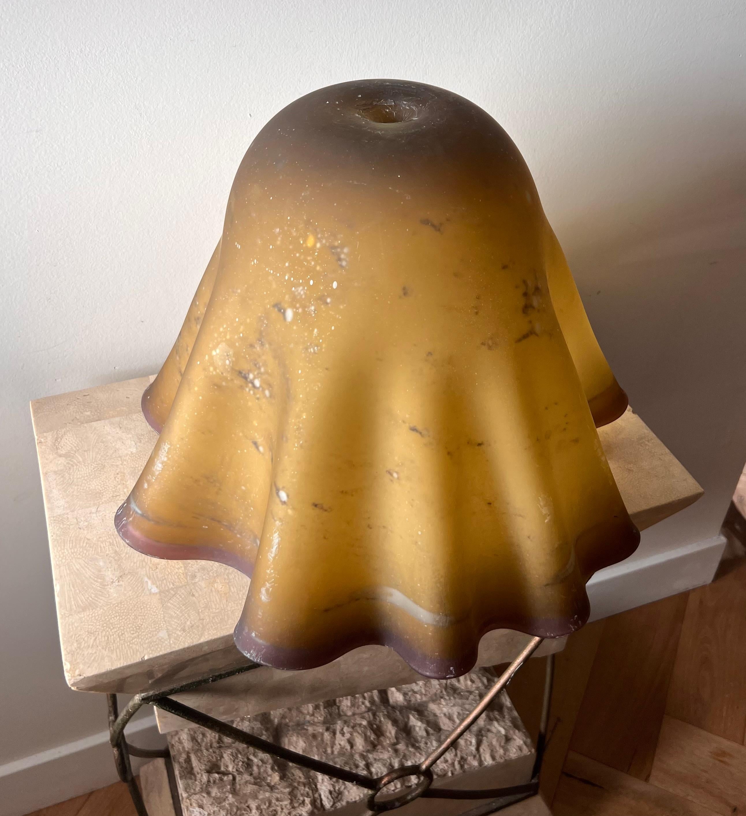 A very unique trompe l’œil art glass lamp shade, mid 20th century. Tones of mustard and mauve, and featuring a voluptuous oyster edge in undulating pattern. Some wear and tear but no glaring flaws. Please note this is only the shade - no lamp base.