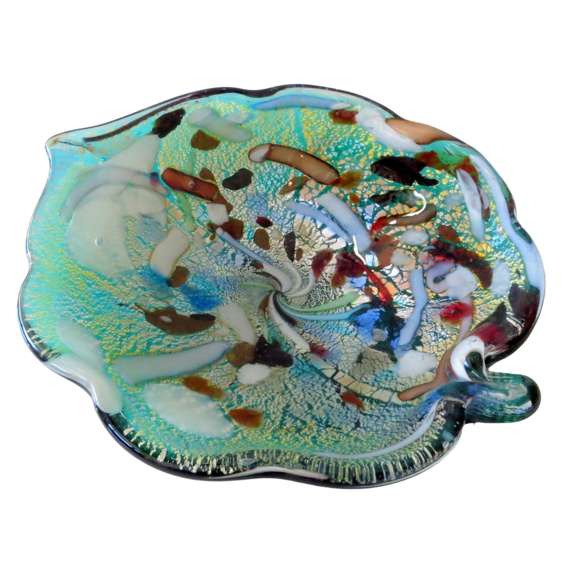 This vintage candy dish is made of teal 'sommerso' art glass with a clear casing, and decorated with various bits of different colored and textured glass. The glass 'confetti' is suspended within the casing above a layer of silver foil, and does not