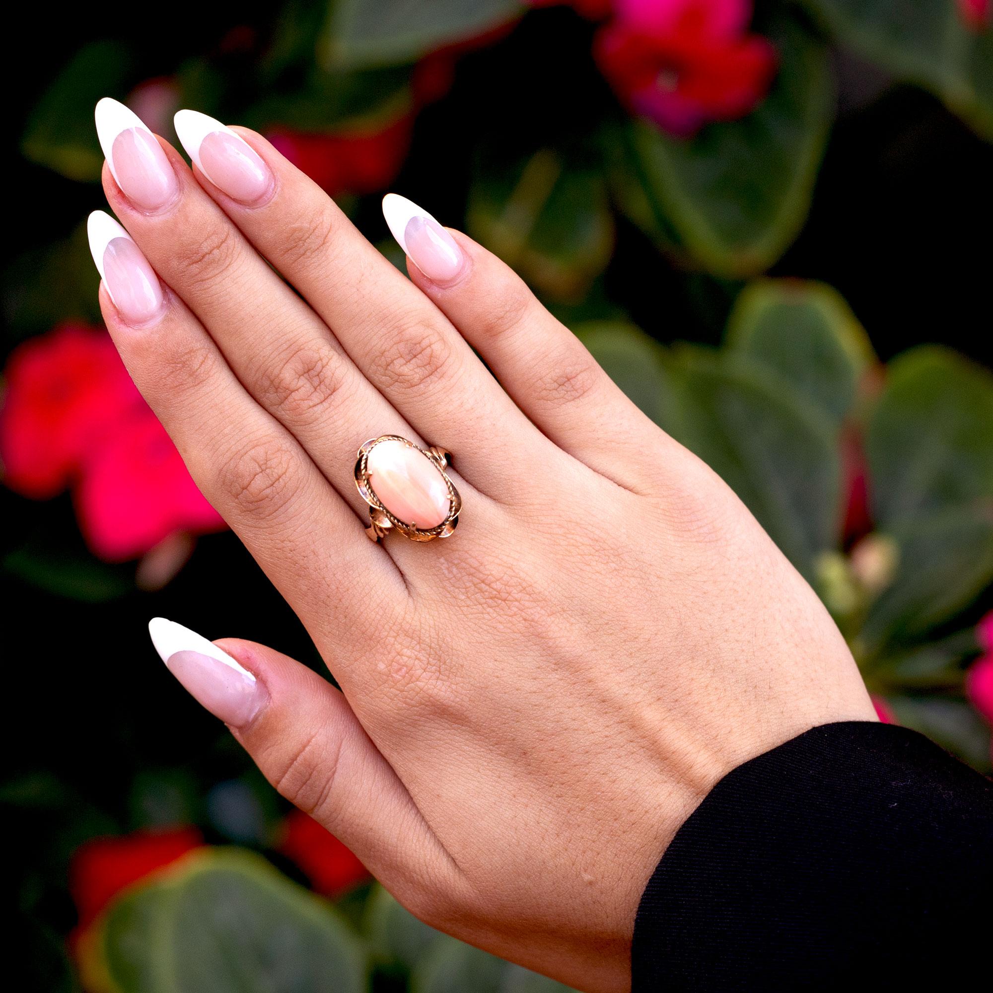 A wonderful, cabochon shaped coral statement ring, hailing from the impactful Art Nouveau period. The circa early 1900s masterpiece features a lovely light angel skin coral, that seems to shift color depending on its setting, breathtaking under both
