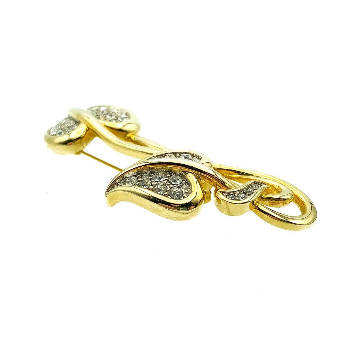 A long and delightfully stylish Vintage Art Nouveau Ivy Brooch. Featuring a double ended trail of ivy encrusted with pave set rhinestones. 
Vintage Condition: Very good without damage or noteworthy wear. 
Materials: Gold plated meta, glass