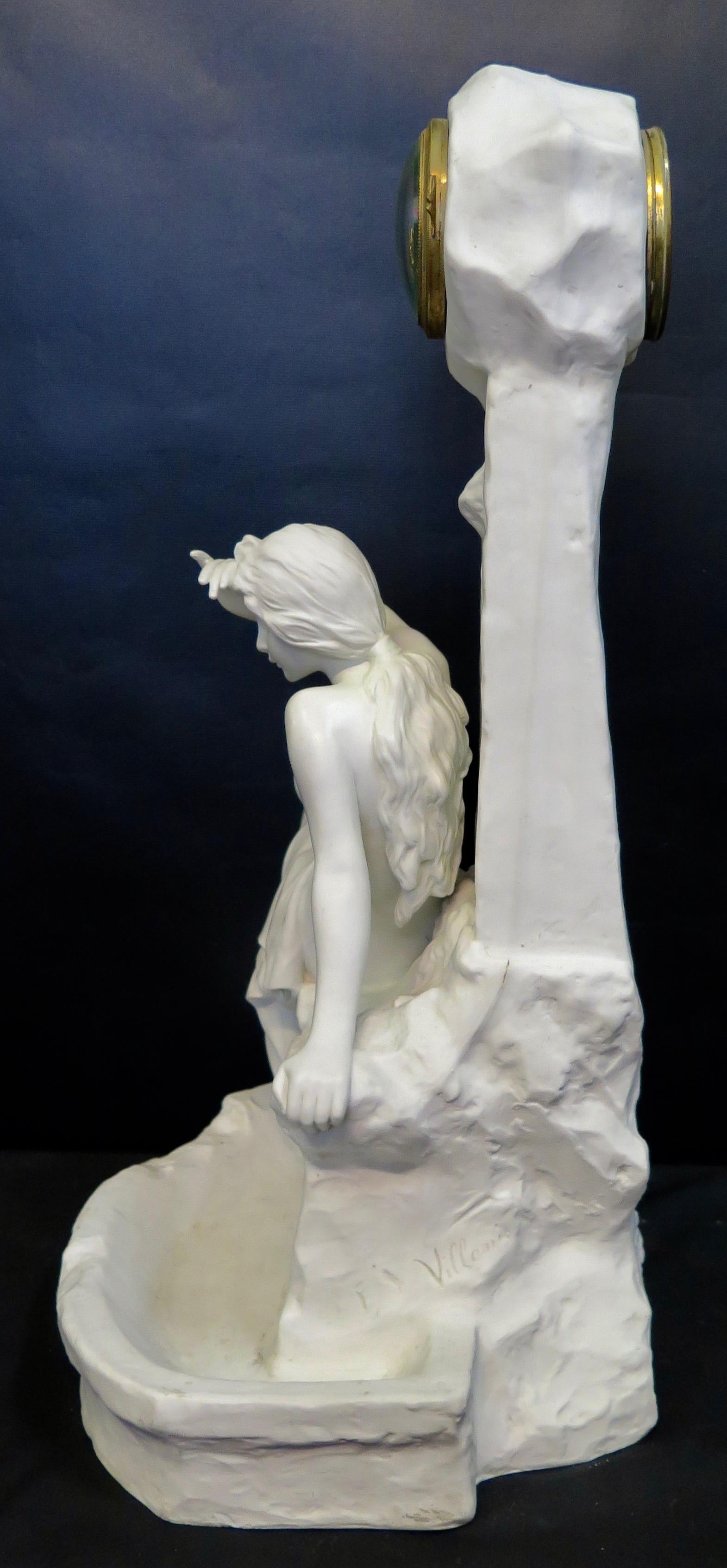 This vintage Art Nouveau sculpture with clock is designed in a hard paste white porcelain. A sensuous young scantily dressed female figure is positioned upon the ledge of the town well. A pensive face sets a somber mood. A clock is placed within the