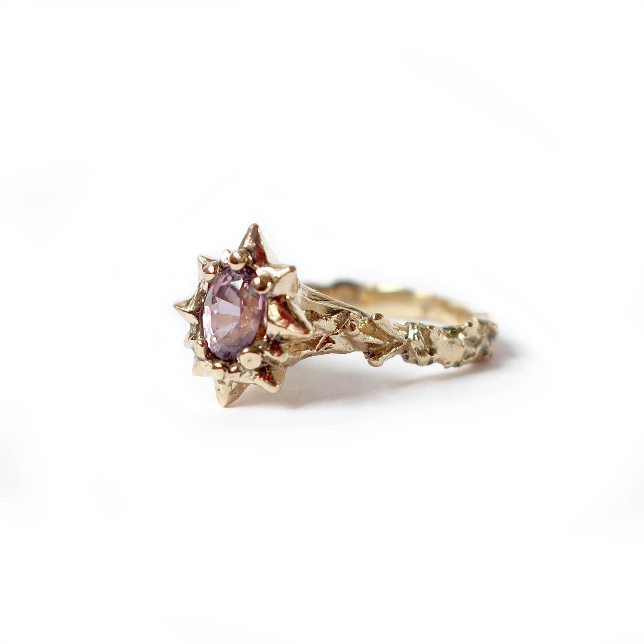 This hand carved 14 carat yellow gold ring features a beautiful oval lavender 6x4mm sapphire gemstone. This ring showcases a thistle like band texture and setting. 

Size 6.25