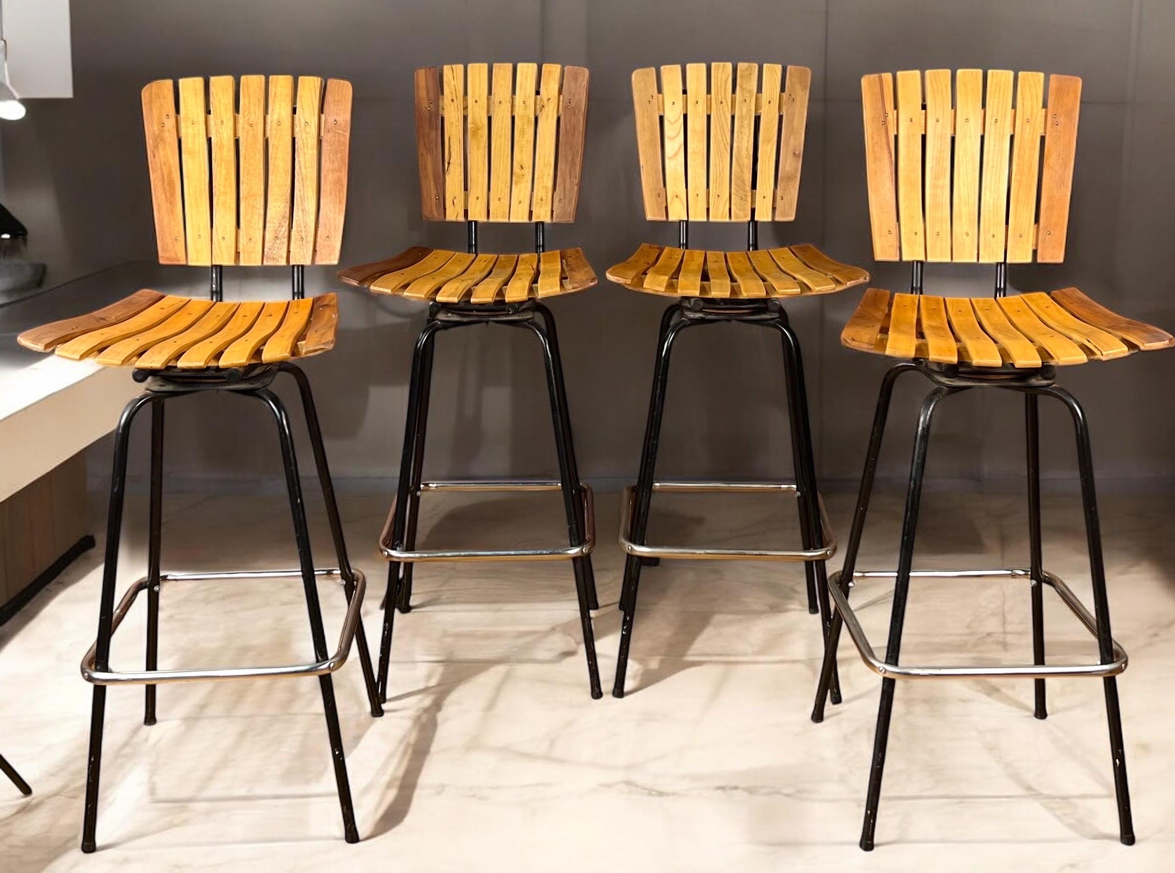 Available for sale is a charming set of vintage stools inspired by Umanoff. These stools feature metal frames complemented by wooden slat seats.