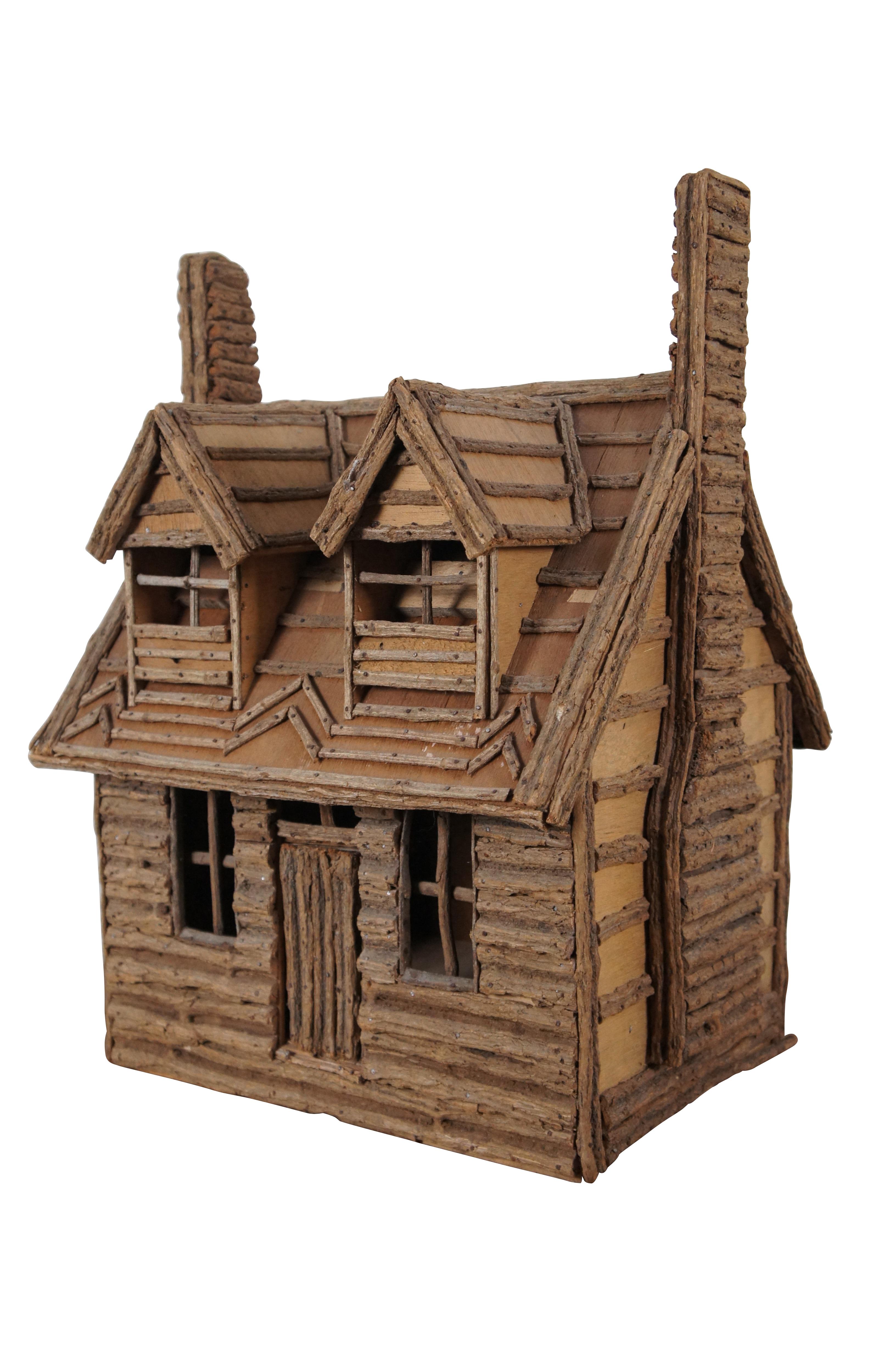Primitive style Adirondack style log cabin.  Made from wood, sticks and bark.  Features a central door flanked by two windows.  The upper story shows two windows and two chimneys.

Dimensions:
17.25” x 15.75” x 23” (Width x Depth x Height)