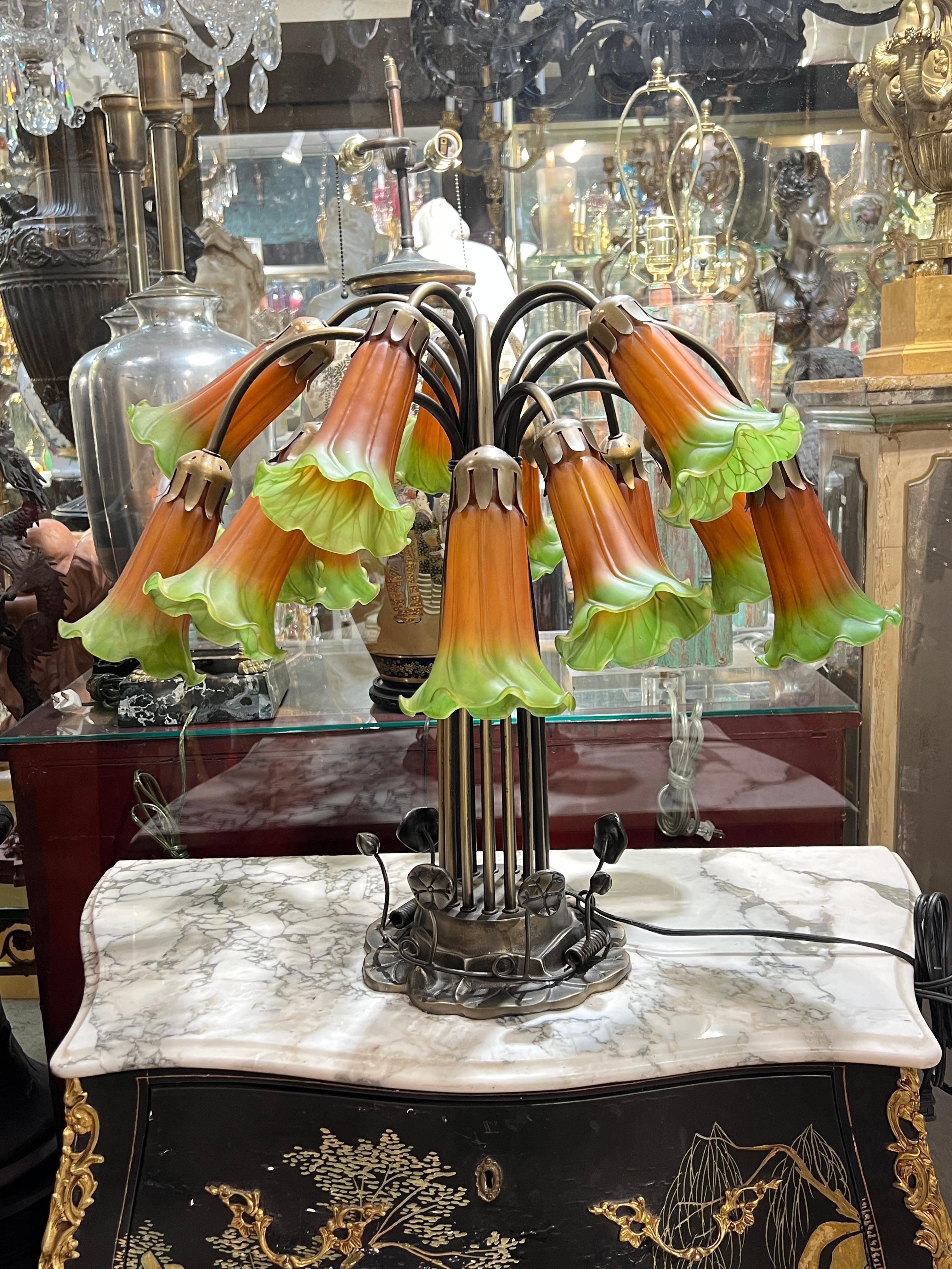 Vintage Arts and Crafts Tiffany style table lamp in patinated metal with 15 candelabra size sockets with beautiful tulip flower-shaped orange and green glass shades emanating from a lily pad-form base.  Ready for use.