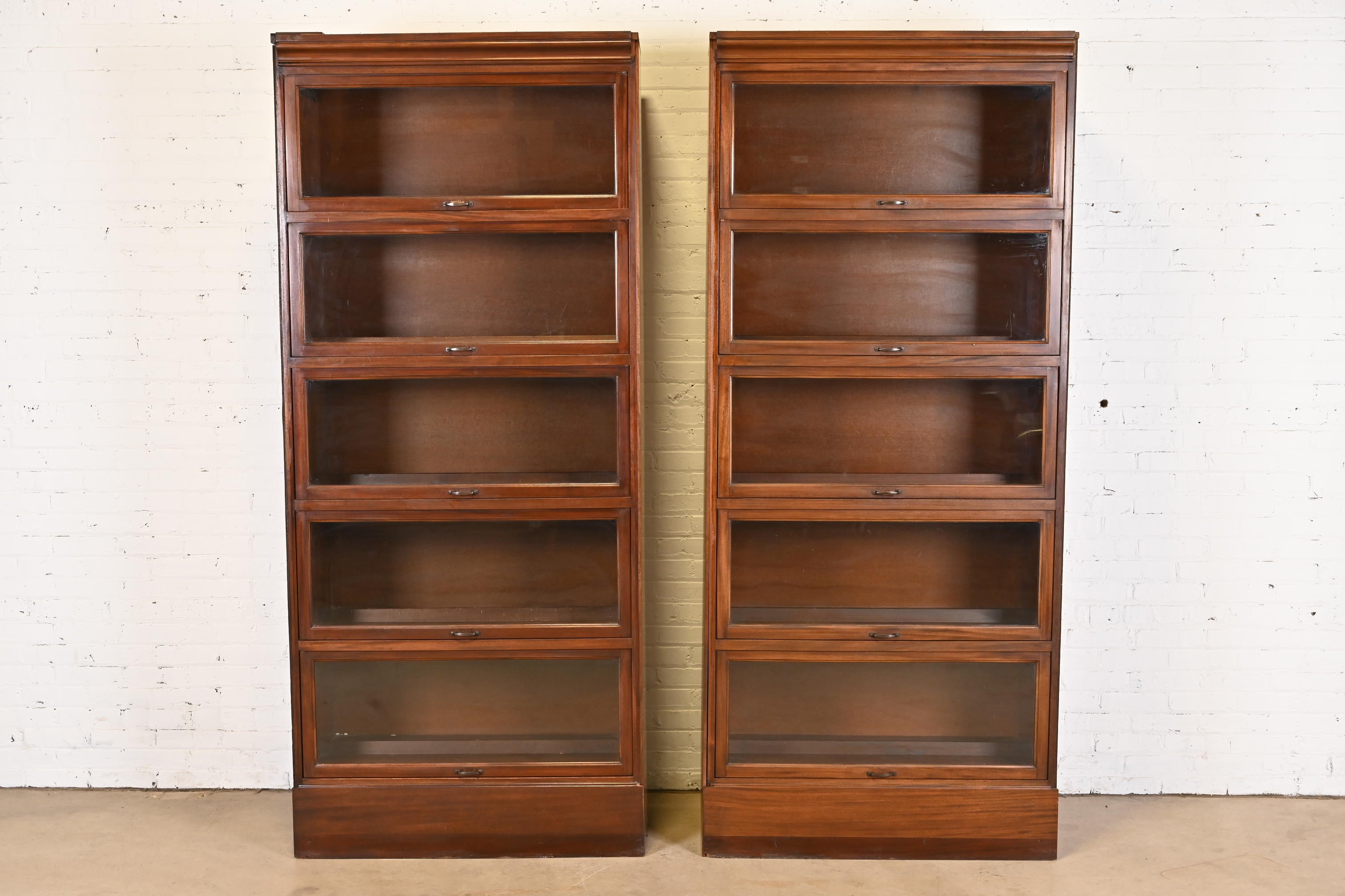 A gorgeous pair of vintage Arts & Crafts large five-stack barrister bookcases

In the manner of Globe Wernicke

USA, Mid-20th Century

Mahogany, with glass front doors and brass hardware.

Measures: 38.88