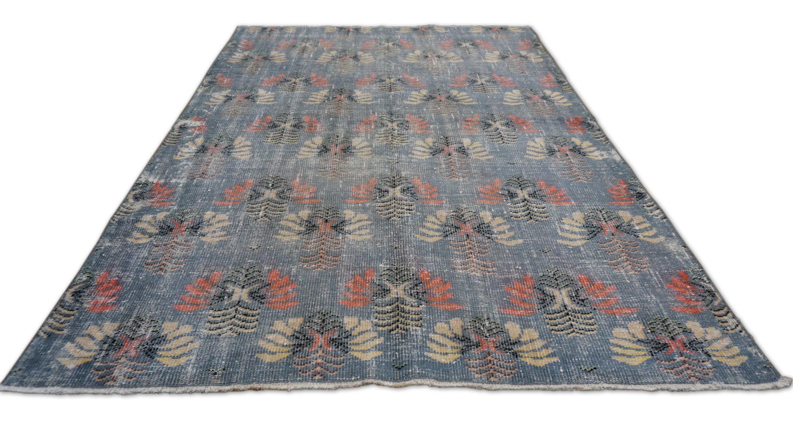 Dieser handgeknüpfte Wollteppich zeigt eine charmante Mischung aus traditionellen Motiven und gealterter Eleganz. Das zarte, sich wiederholende florale Medaillonmuster wird durch Gelb, Koralle, Grau und Schwarz akzentuiert und verleiht dem Teppich