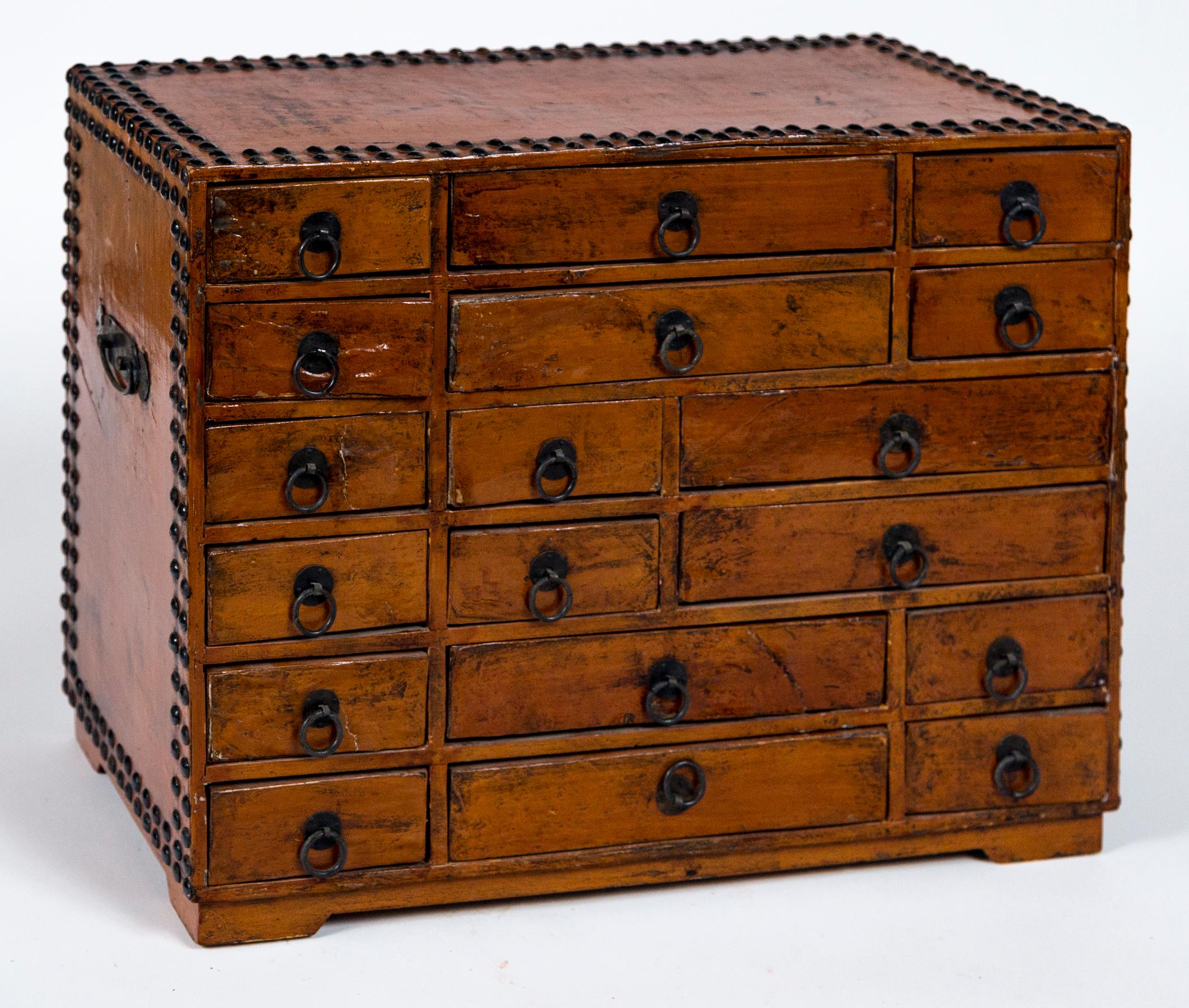 Vintage Asian Apothecary Chest, 20th Century. Chest has a narrow footed base, and 18 fabric lined drawers with metal pulls. Double rows of nail heads outlining top and sides, with 2 iron handles.