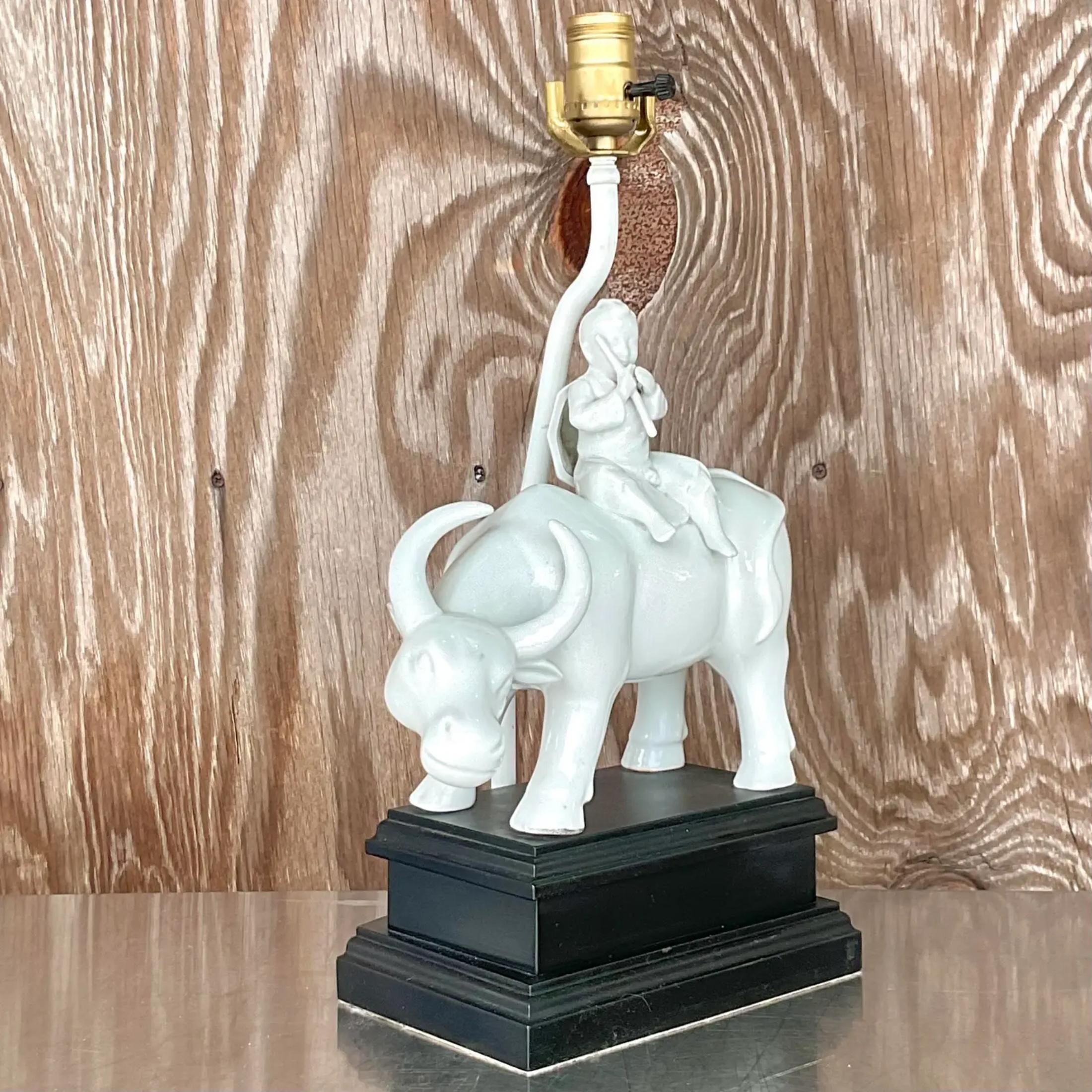 Fabulous vintage Blanc De Chine table lamp. A beautiful white glazed ceramic on a black wooden plinth. A small boy with his flute riding his bull. Acquired from a Palm Beach estate