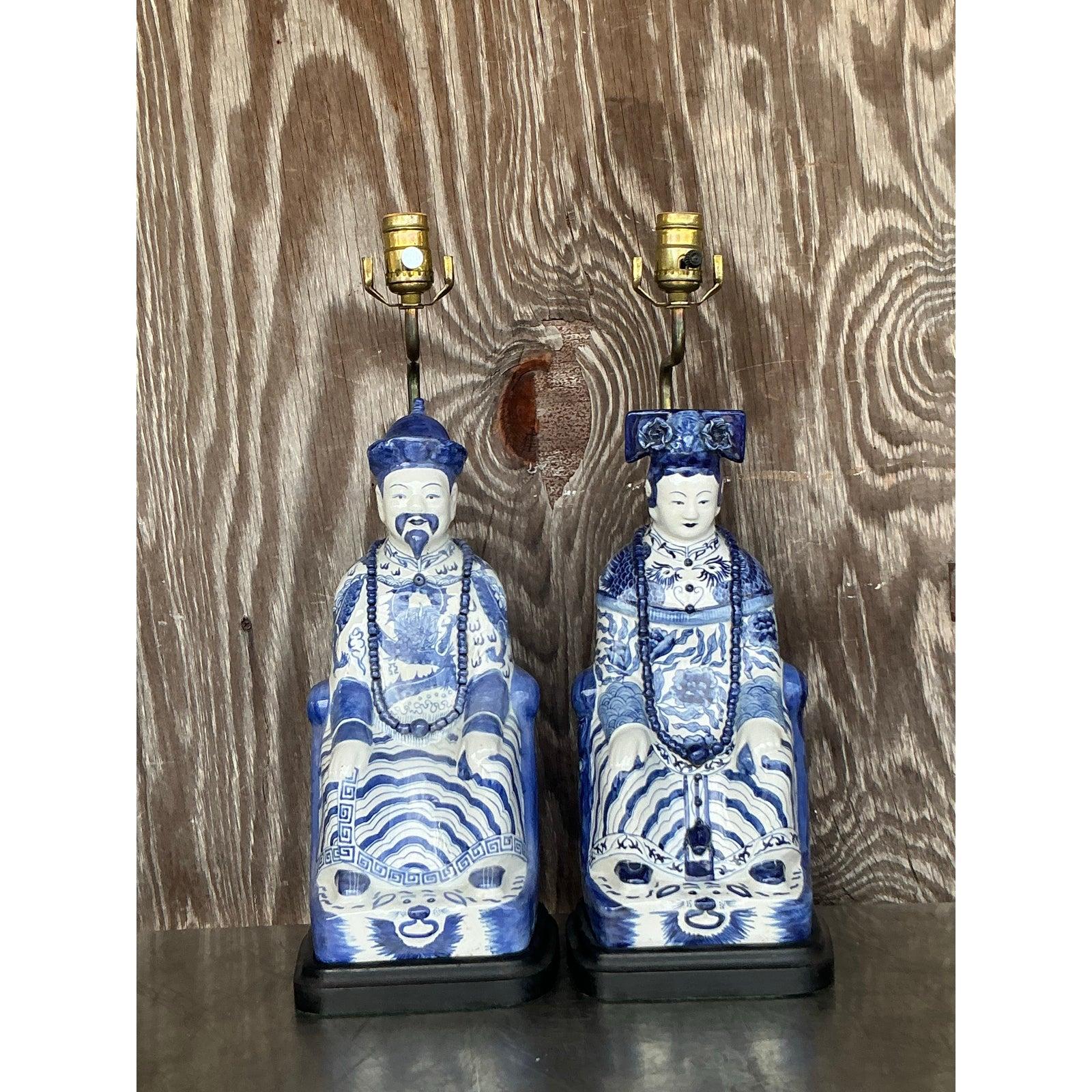 Make a bold statement with this captivating pair of vintage Asian emperor lamps, exquisitely crafted in a timeless blue and white palette. Each lamp depicts a seated imperial figure, hand-painted with intricate robes, symbolic details, and striking